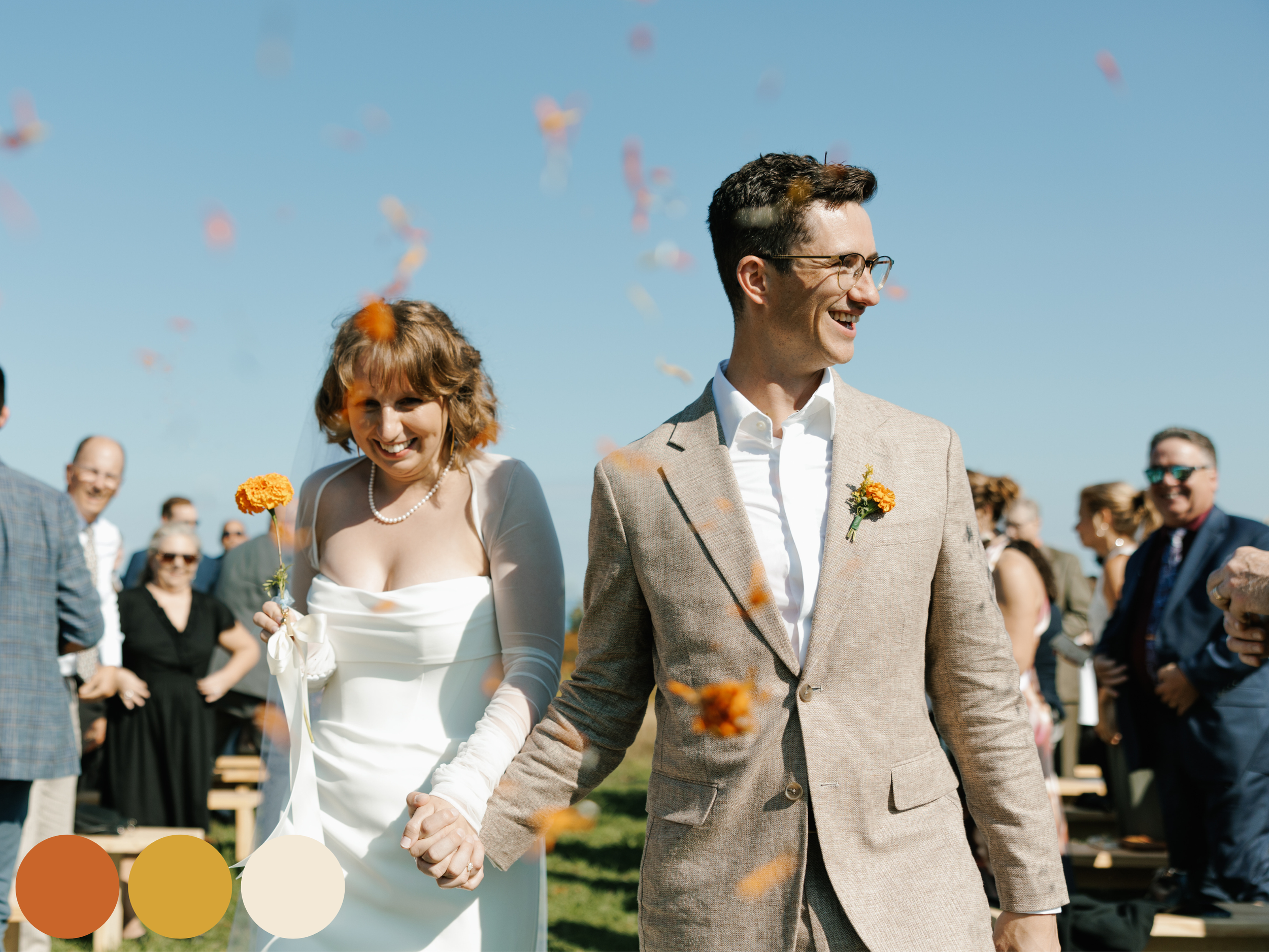 bride and groom walking down the aisle as guests toss petals, featuring a September wedding color palette with warm orange blooms and a joyful fall wedding flower palette