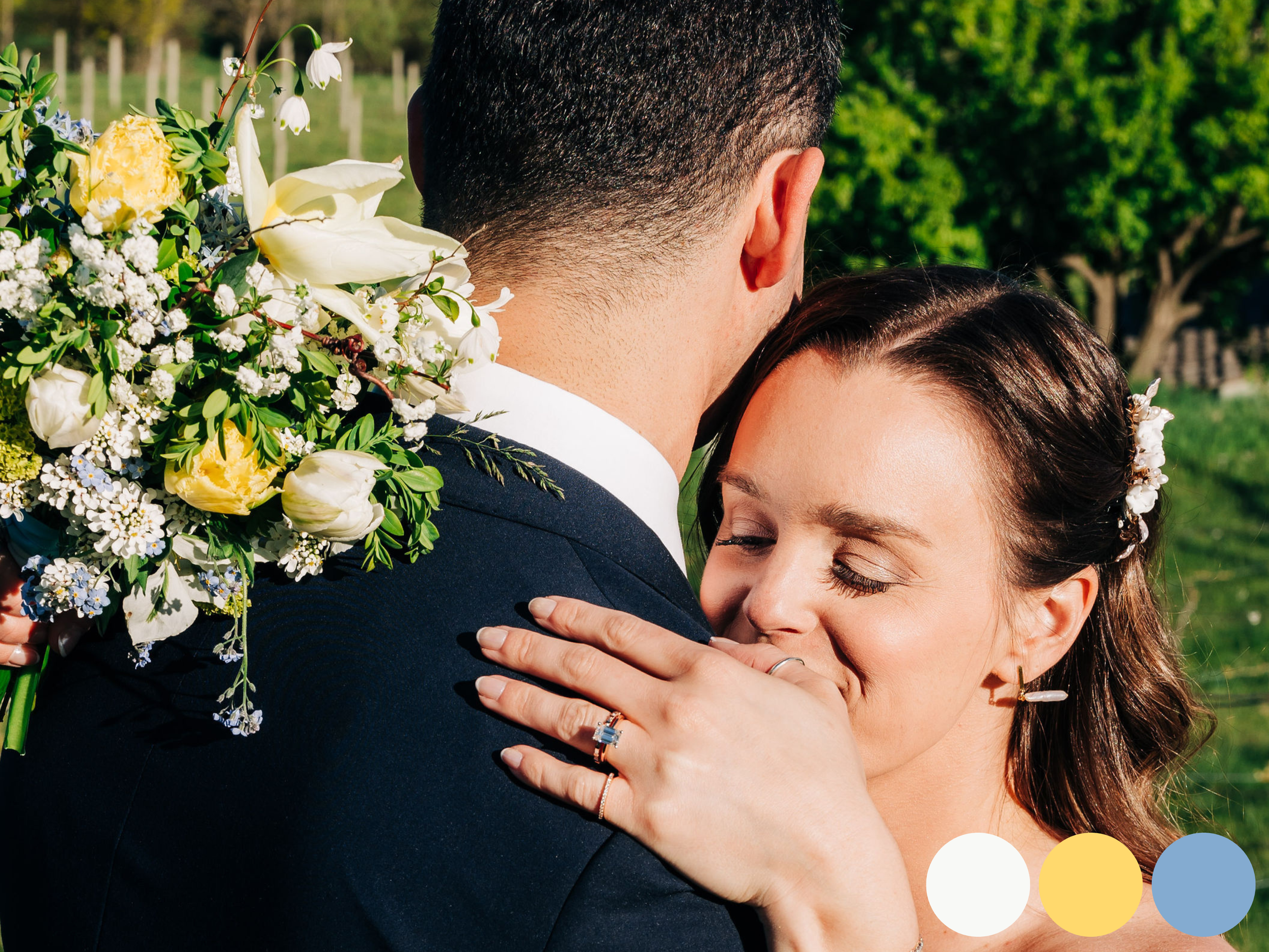 Intimate couple embrace with spring wedding flowers featuring a natural garden style bridal bouquet in white, soft yellow and fresh greenery