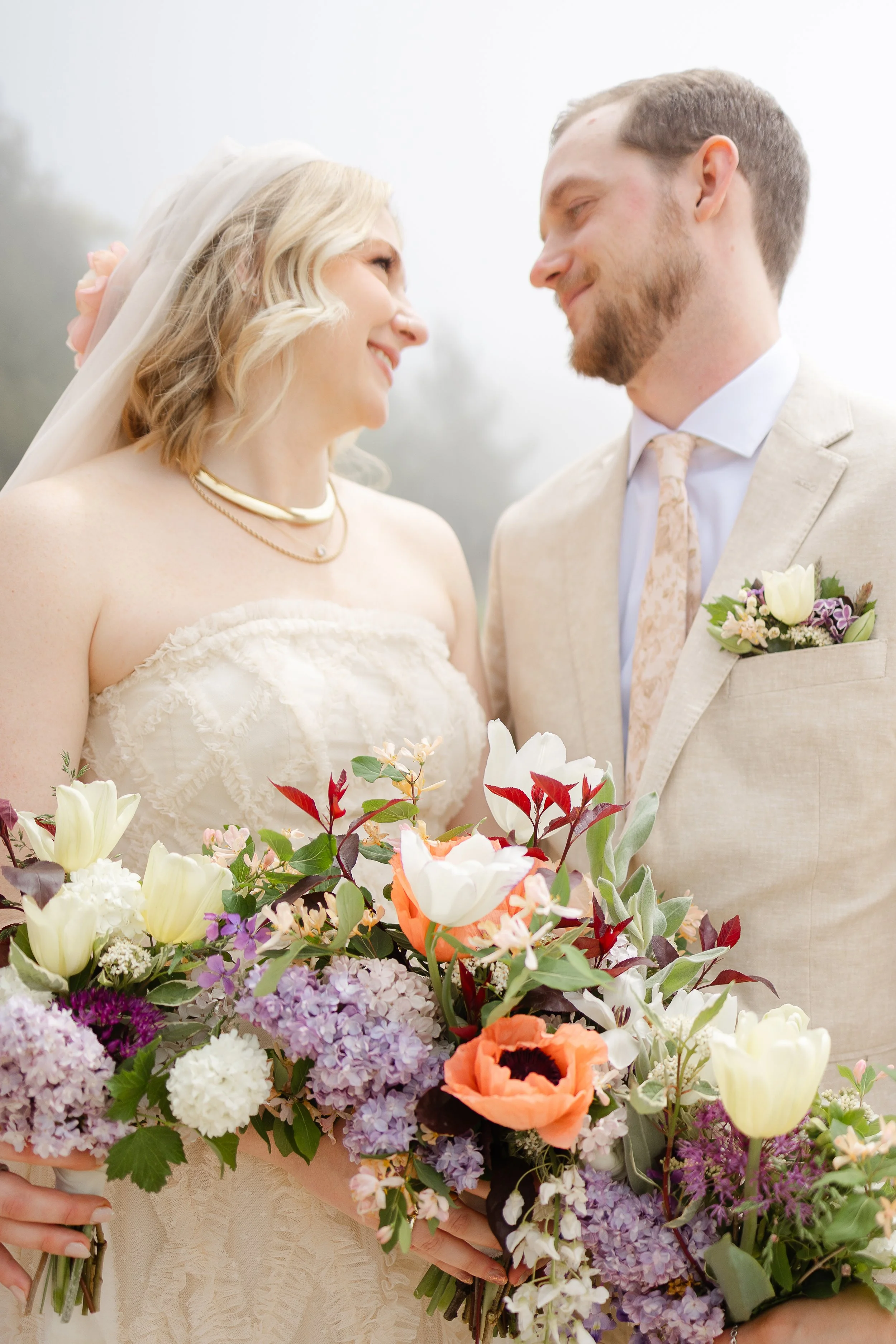 Bride and groom holding a colorful seasonal flower bouquet at their Northern Michigan wedding