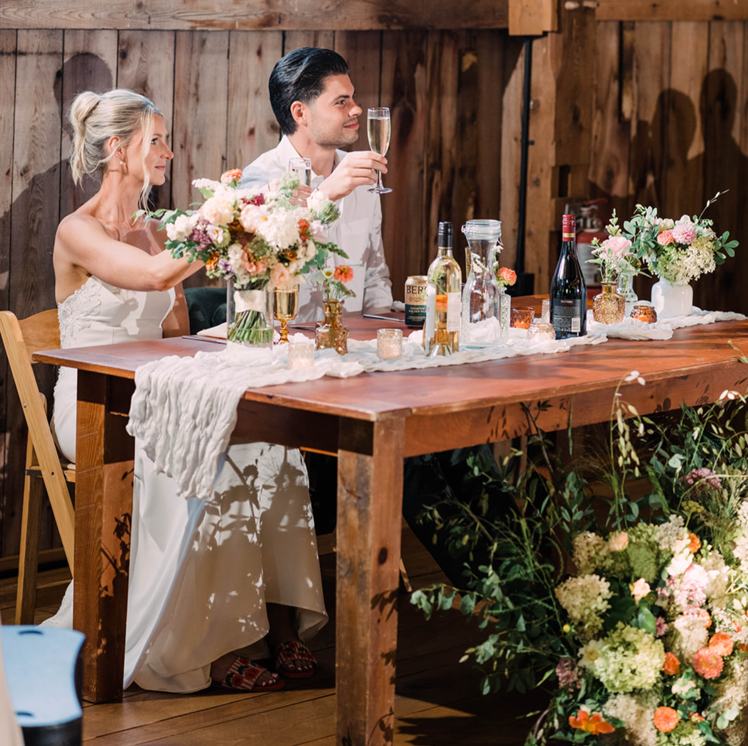 Bride and groom at sweetheart table with seasonal floral arrangements and soft, natural wedding table design
