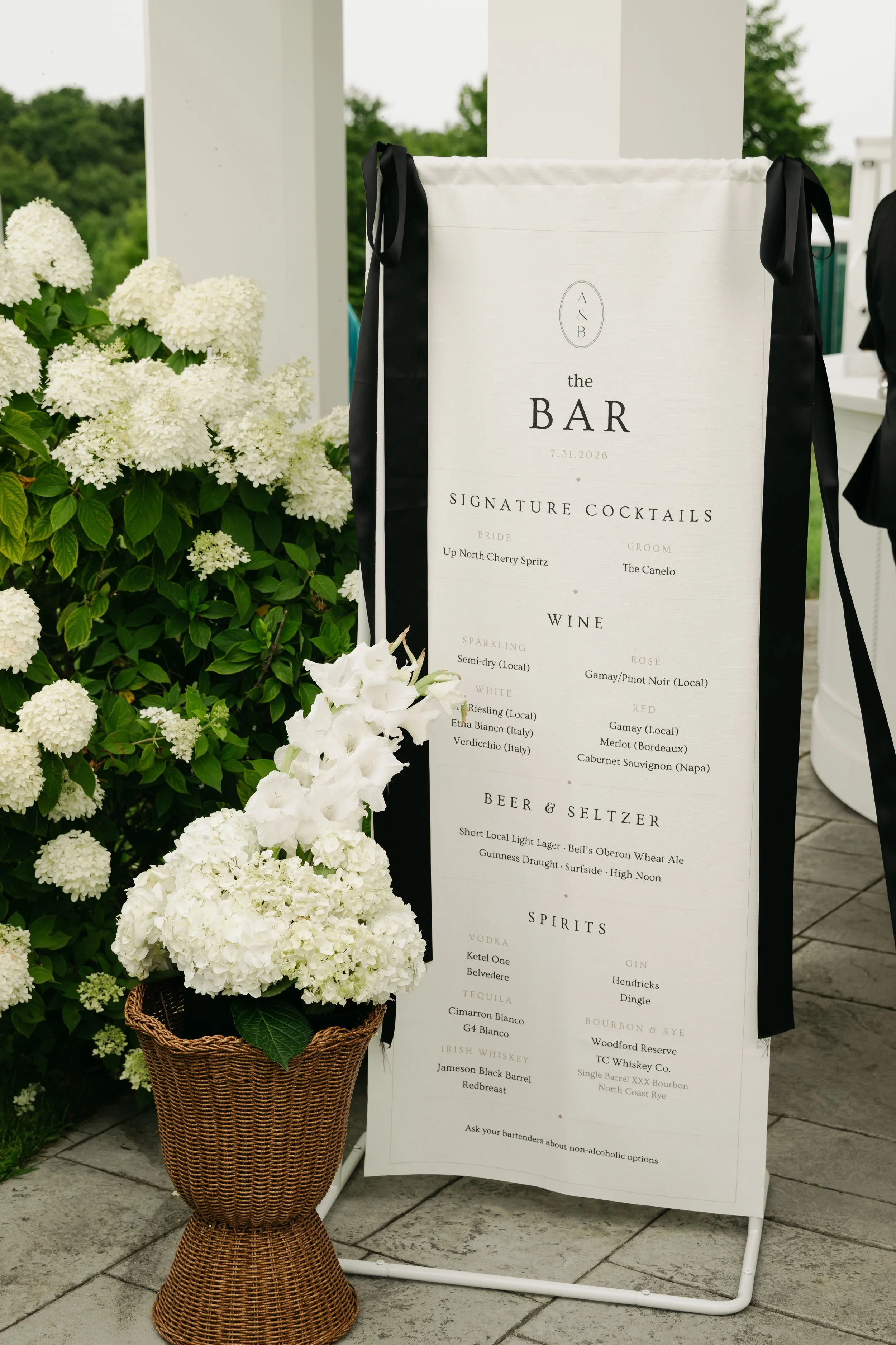 Wedding bar sign accented with a basket of white hydrangeas and seasonal flowers at the Conway wedding
