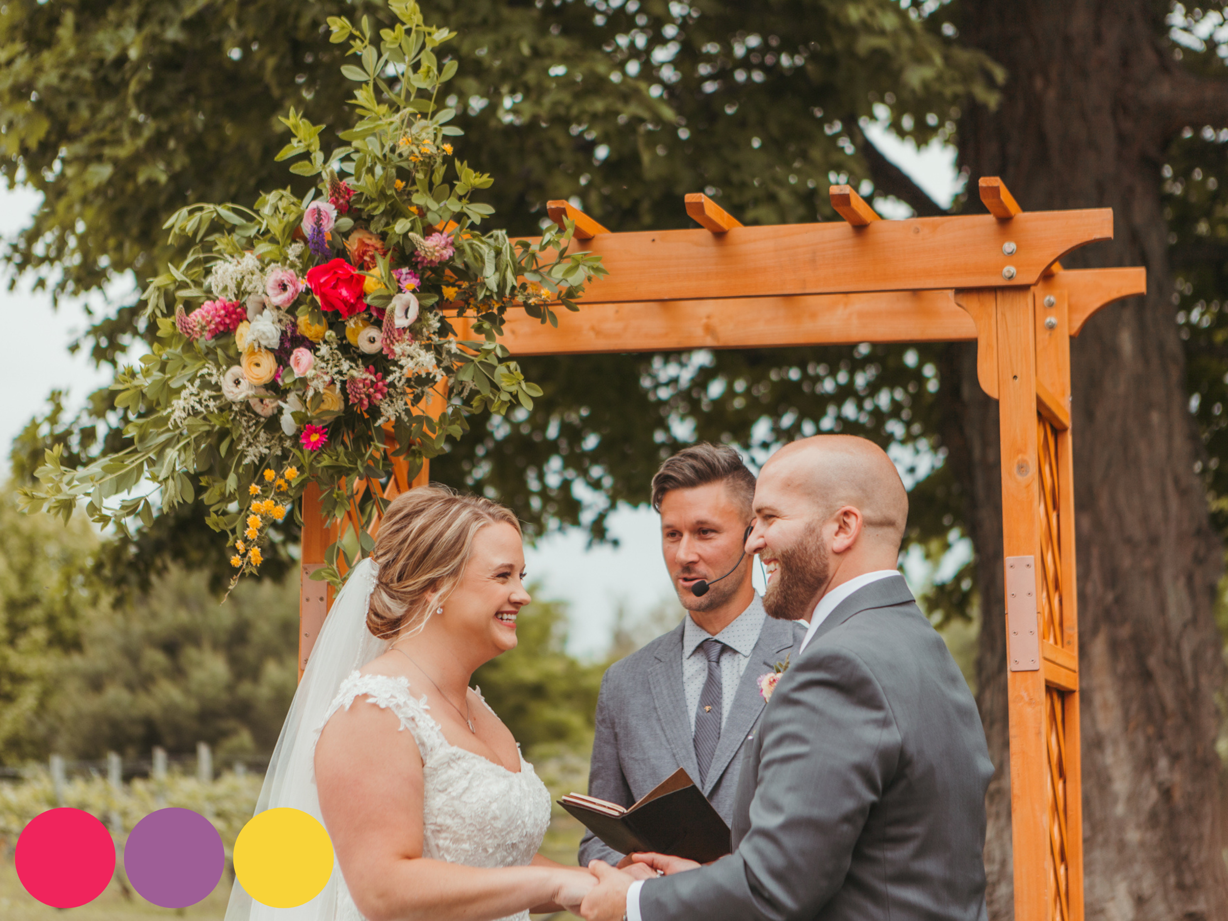 spring wedding ceremony flowers with bride and groom under a wooden arch featuring spring wedding flowers in a bold spring wedding color palette