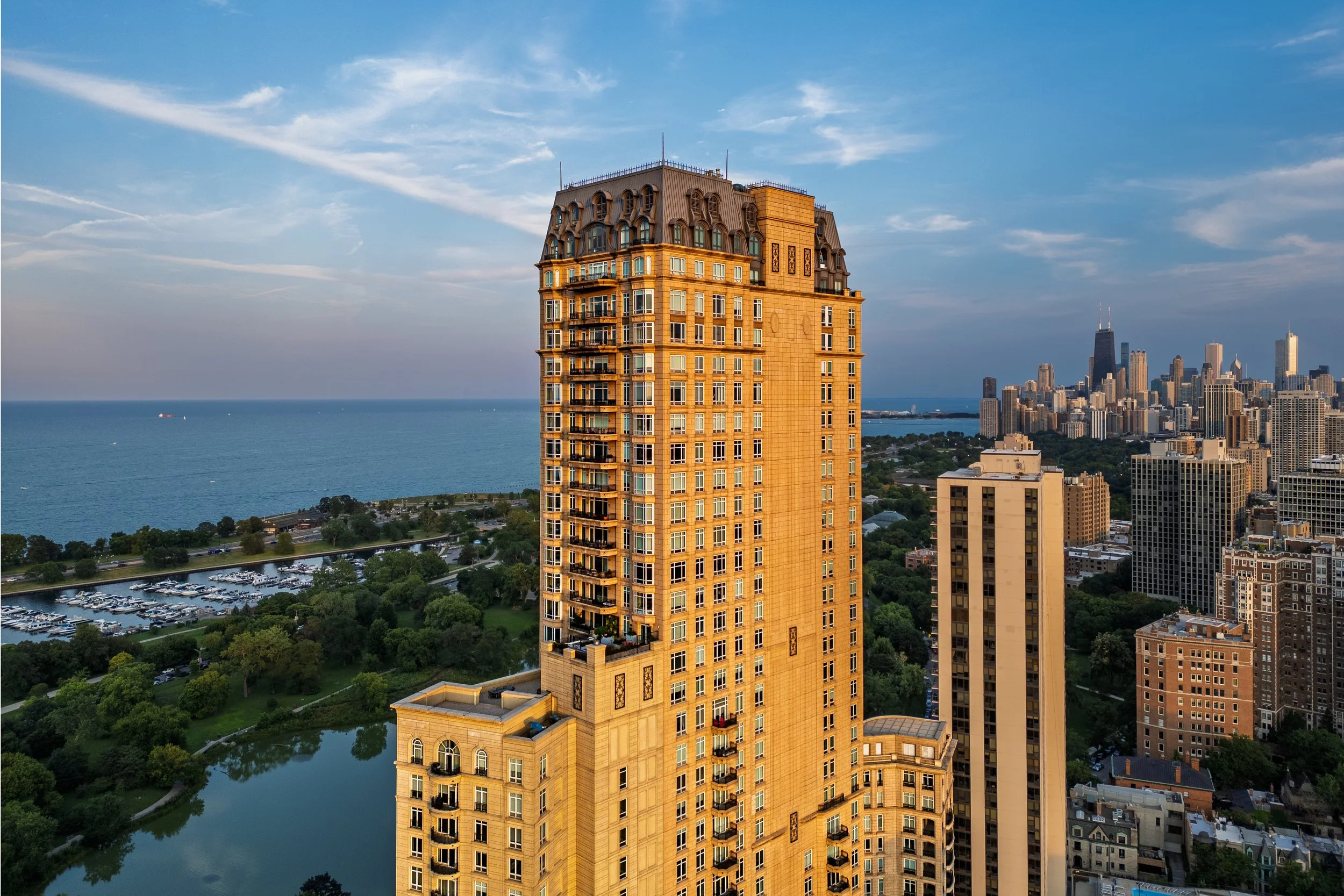 A tall yellow building with a rounded, ornate roof, overlooking a cityscape with high-rise buildings and a body of water in the background.
