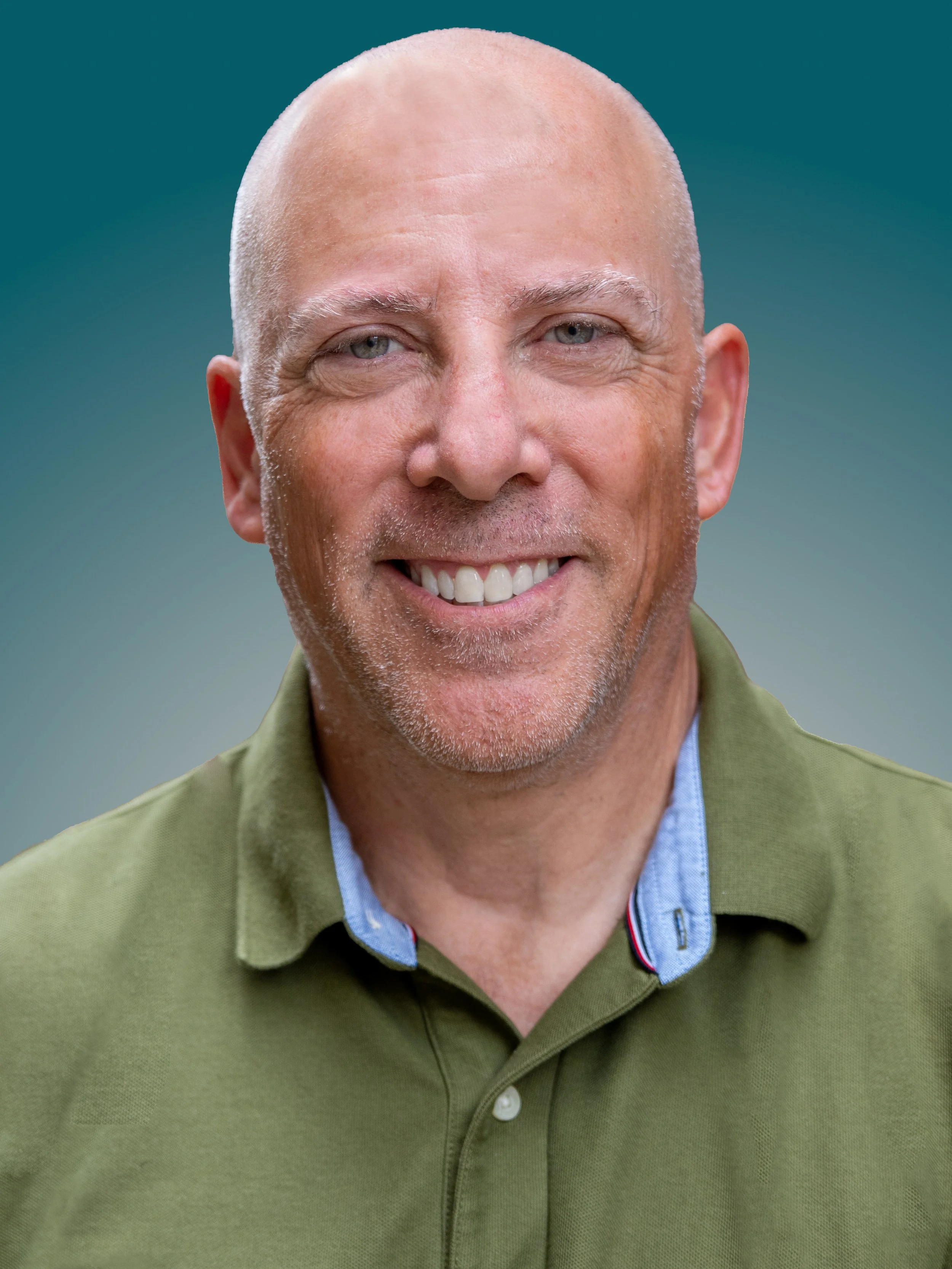 Close-up photo of smiling middle-aged man with bald head, light-colored eyes, and a slight stubble, wearing a green collared shirt.