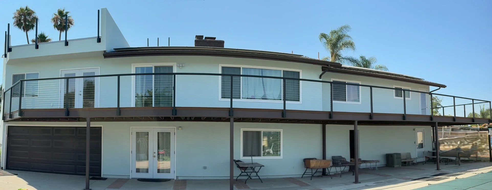 Completed under deck waterproofing project featuring finished soffit ceiling, recessed lighting, and dry patio space below elevated deck.