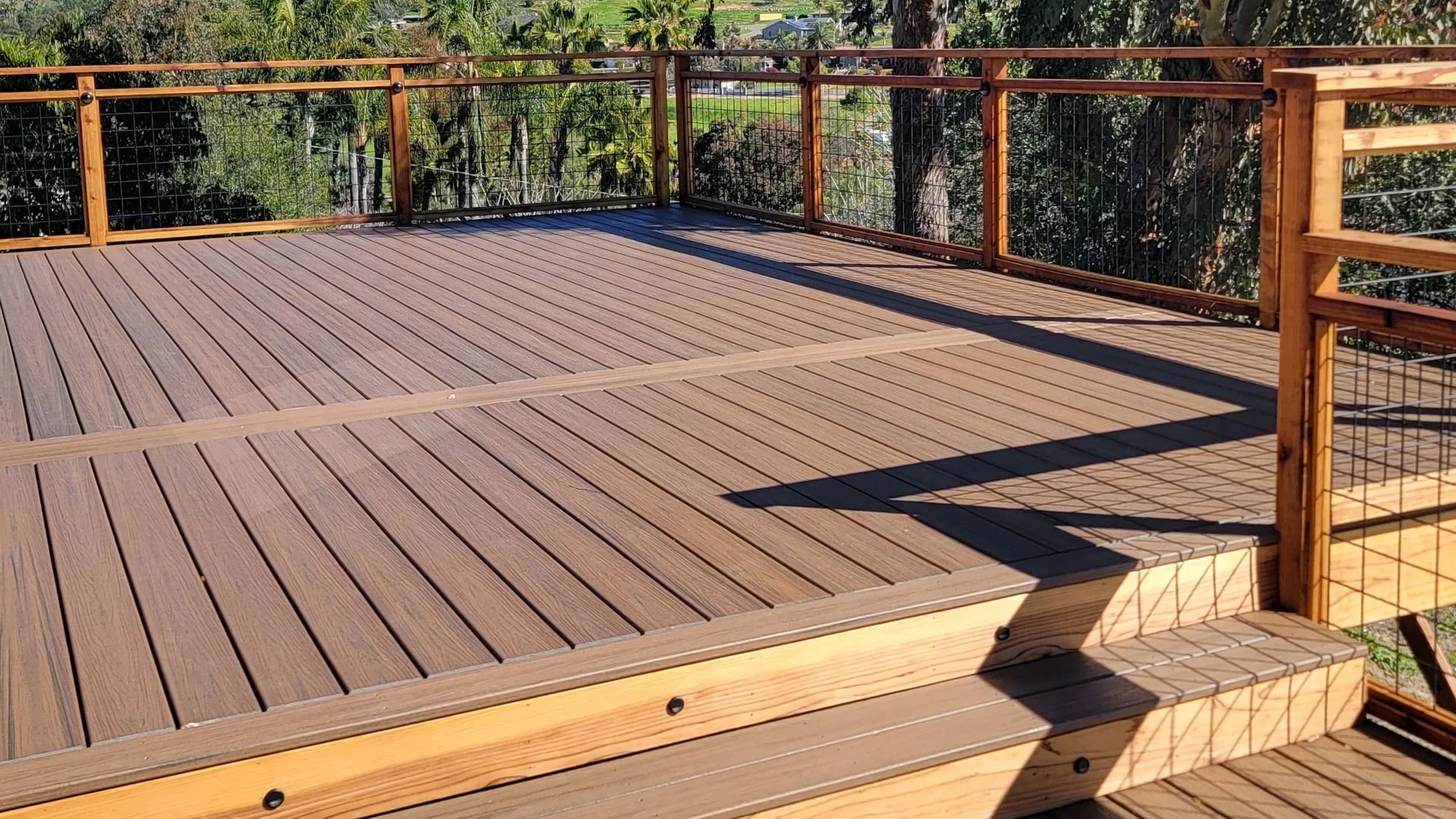 Custom wood deck railing installed on backyard outdoor living deck creating traditional architectural styling and safe usable space.