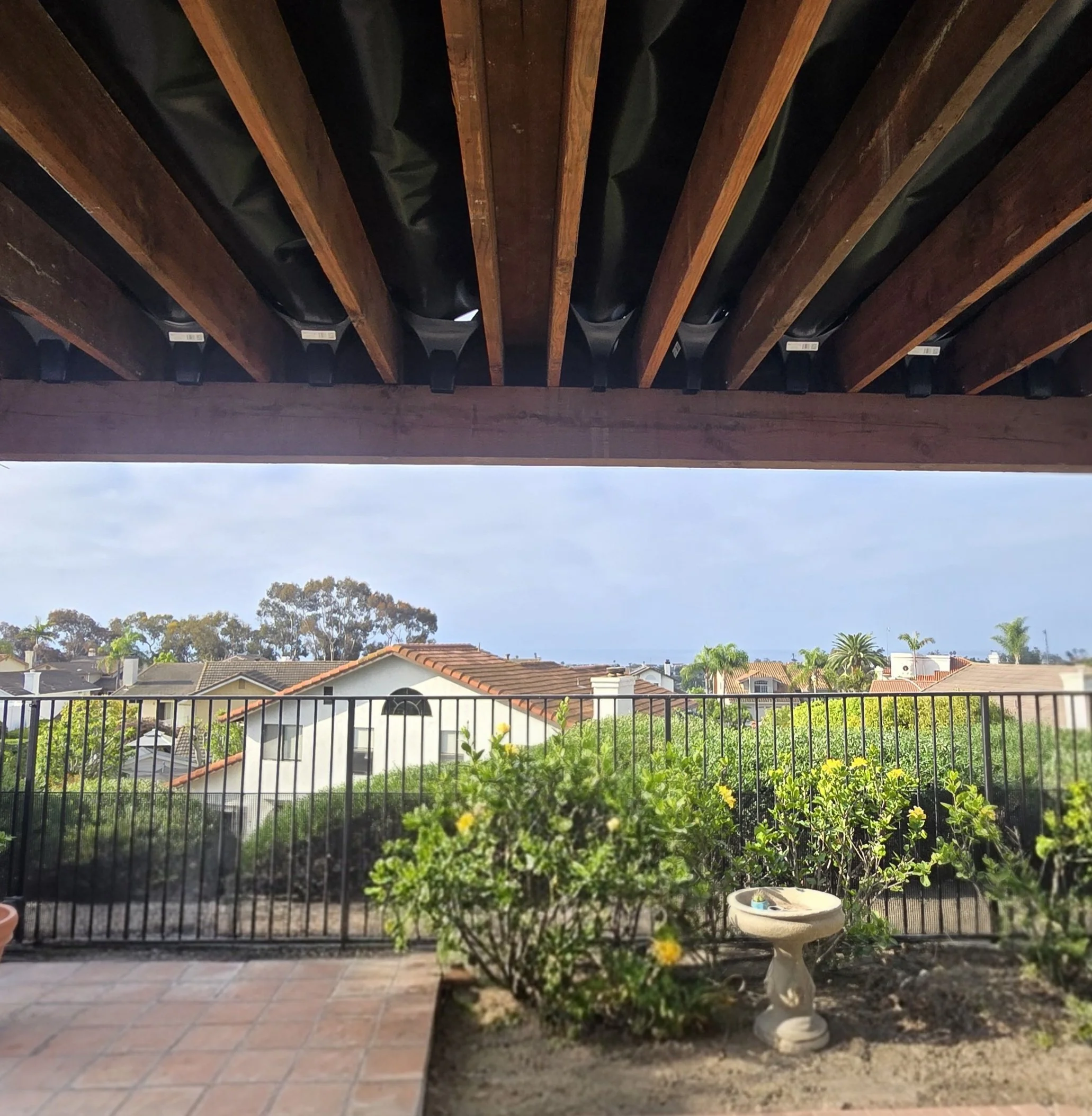 Under deck drainage system installed beneath elevated deck to create dry patio space and protect structural framing.