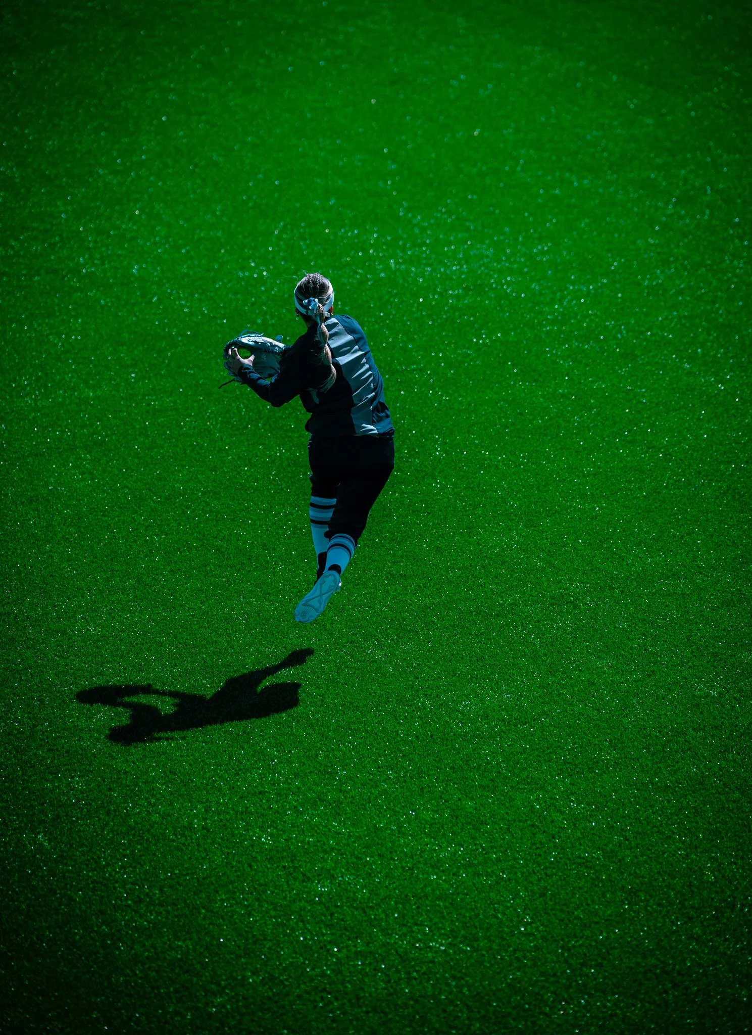 Person playing sports on green field with ball and glove