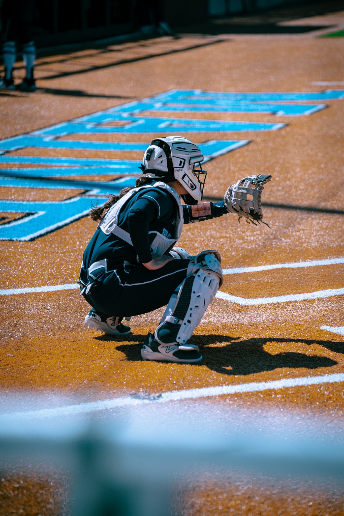 Softball catcher in gear squatting near home plate
