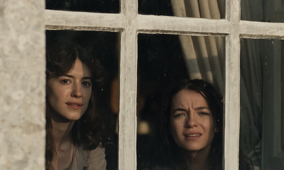 Scène du film Raison et Sentiments (2026) : Elinor et Marianne Dashwood regardent par une fenêtre