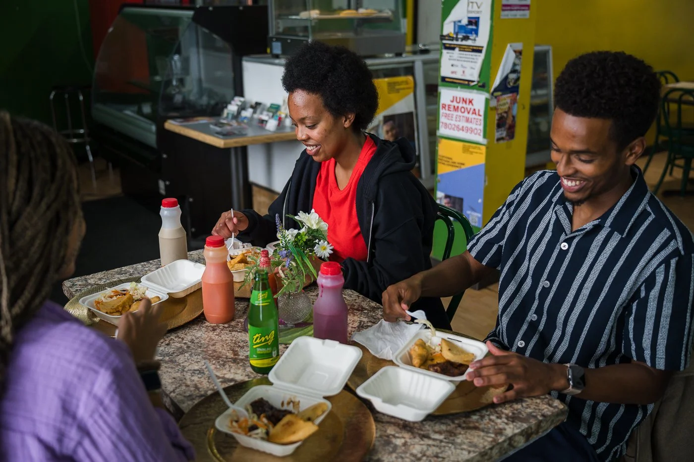 A table of three Black people laughing while enjoying food.