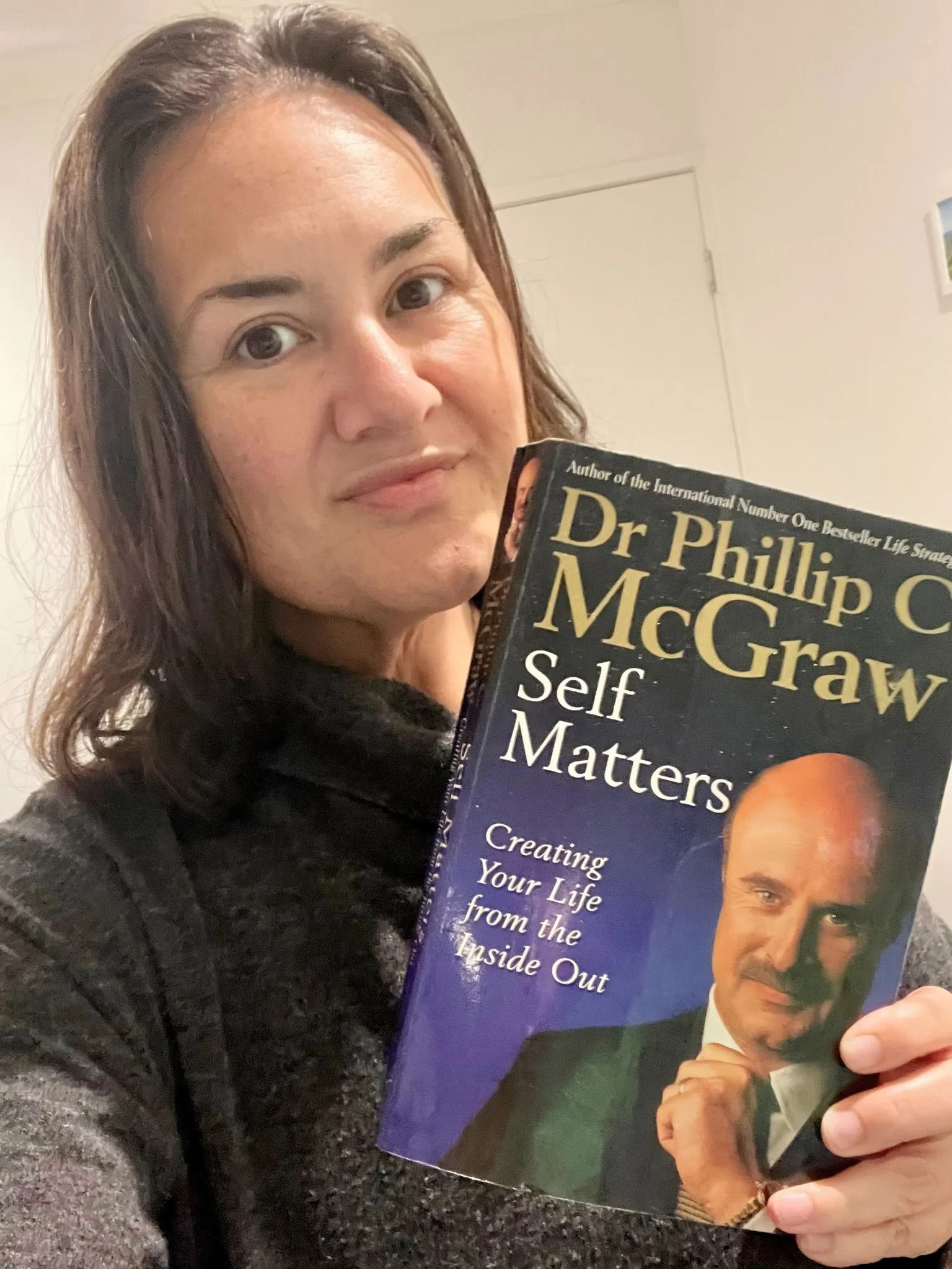 Brown haired woman holding a paperback book by Dr Phil