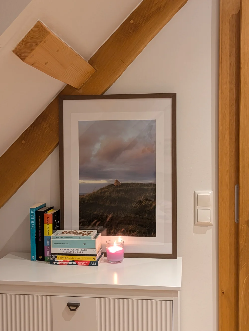 Sheep print on a hilltop, framed on a customer's side table under a sloped ceiling