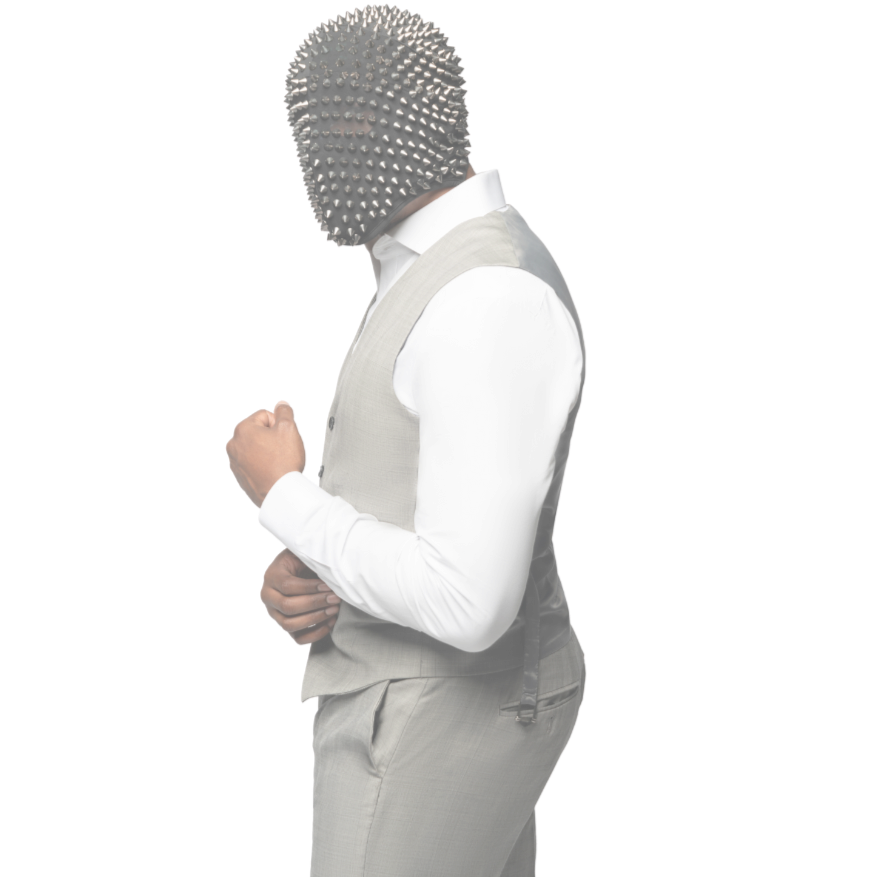 High fashion Clean Peen Eugene.  A man wearing a featureless, studded black mask, a white dress shirt, a light gray vest, and matching gray dress pants, standing in a side profile with his right fist clenched.
