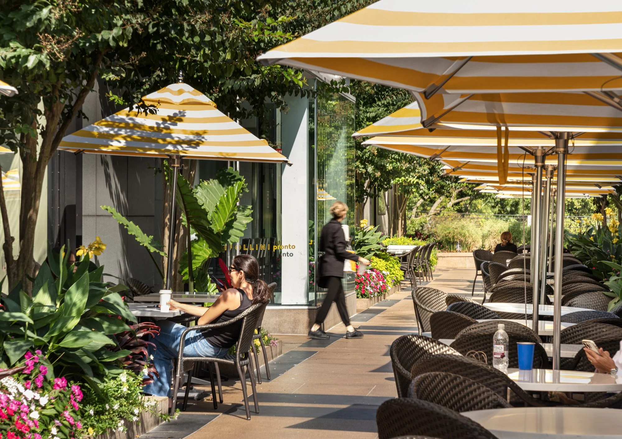 Outdoor dining terrace with striped umbrellas and guests at Americana Manhasset, luxury al fresco dining photography, Manhasset NY — Pavel Bendov Photography