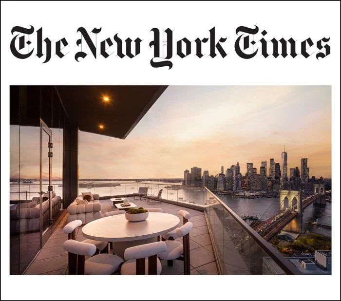A luxury balcony with white furniture and a view of New York City skyline at sunset.