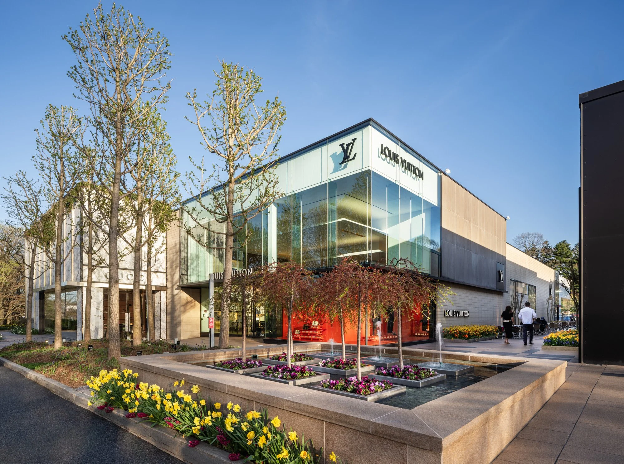 Louis Vuitton flagship exterior at Americana Manhasset with glass curtain wall and spring tulips, Manhasset NY — architectural retail photography by Pavel Bendov