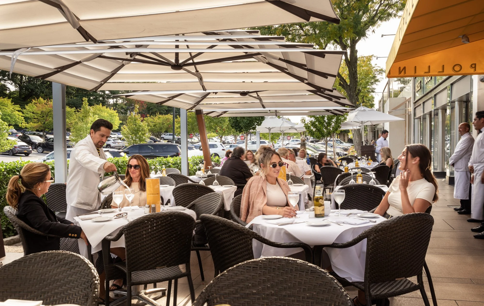 Guests dining on outdoor terrace with waiter at Americana Manhasset, luxury restaurant lifestyle photography, Long Island NY — Pavel Bendov Photography
