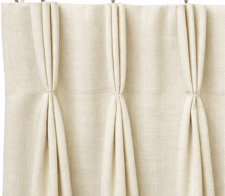 Close-up of beige curtains with triple pleat heading hung on a metal rod.