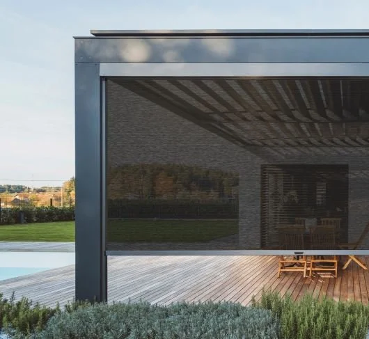 Modern house with a large glass sliding door overlooking a wooden deck and green lawn.