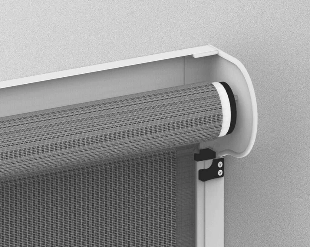 A close-up of a roll-up window or door screen installed inside a frame, with part of a textured wall visible in the background.