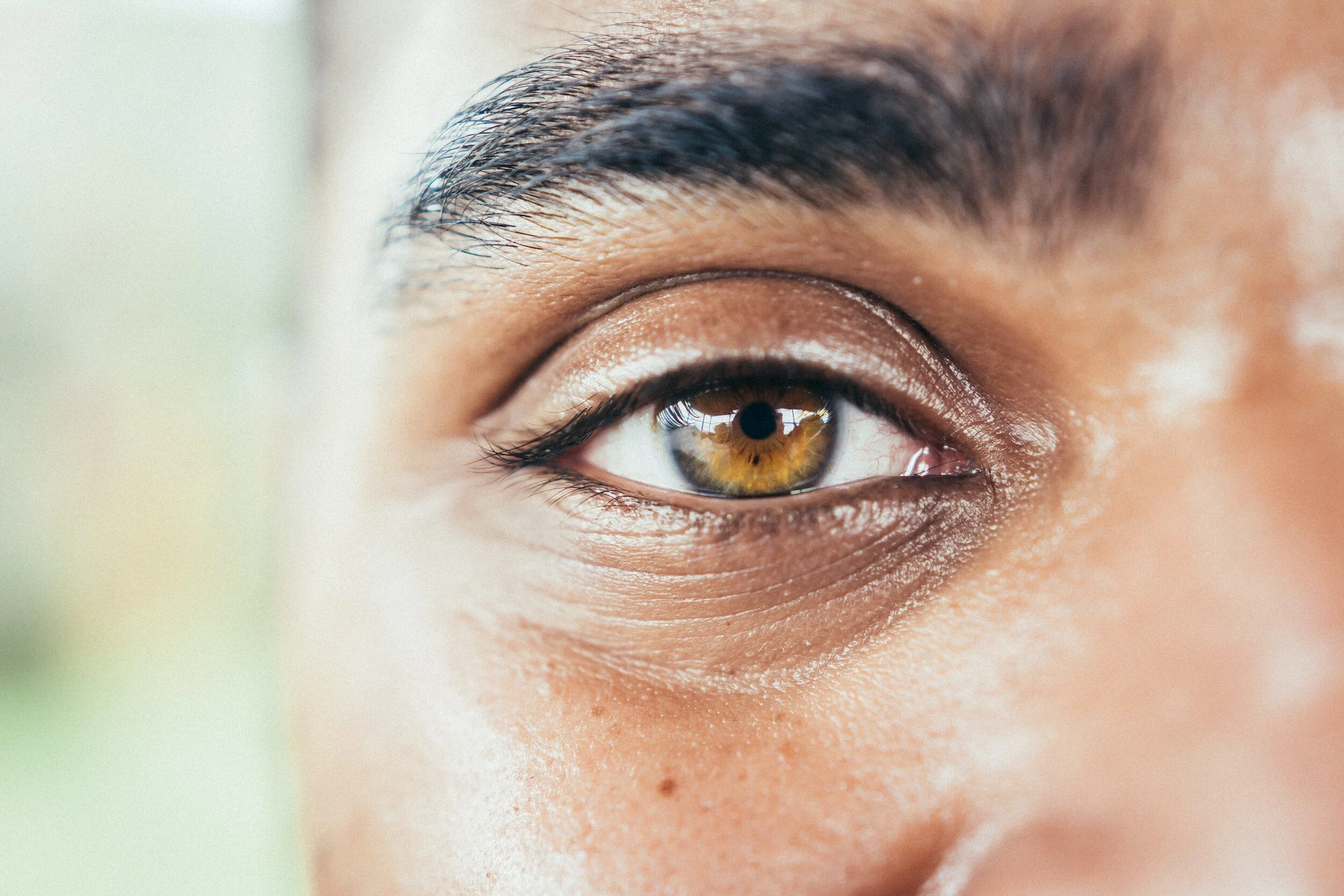 Close-up of a person's brown eye with detailed eyelashes and skin texture.