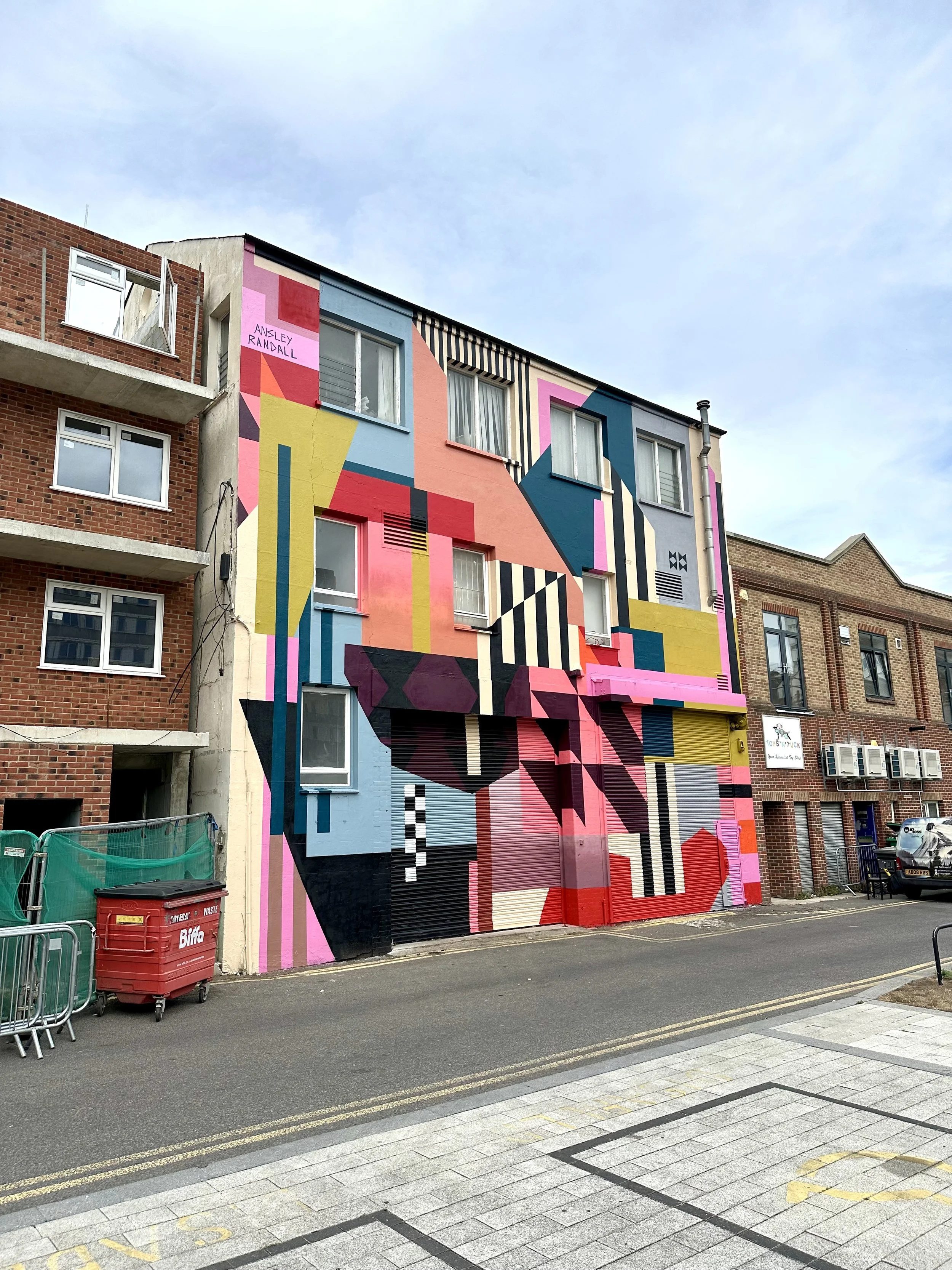 Architectural mural featuring bold geometric shapes and vibrant colors wrapping around a multi-story building façade.