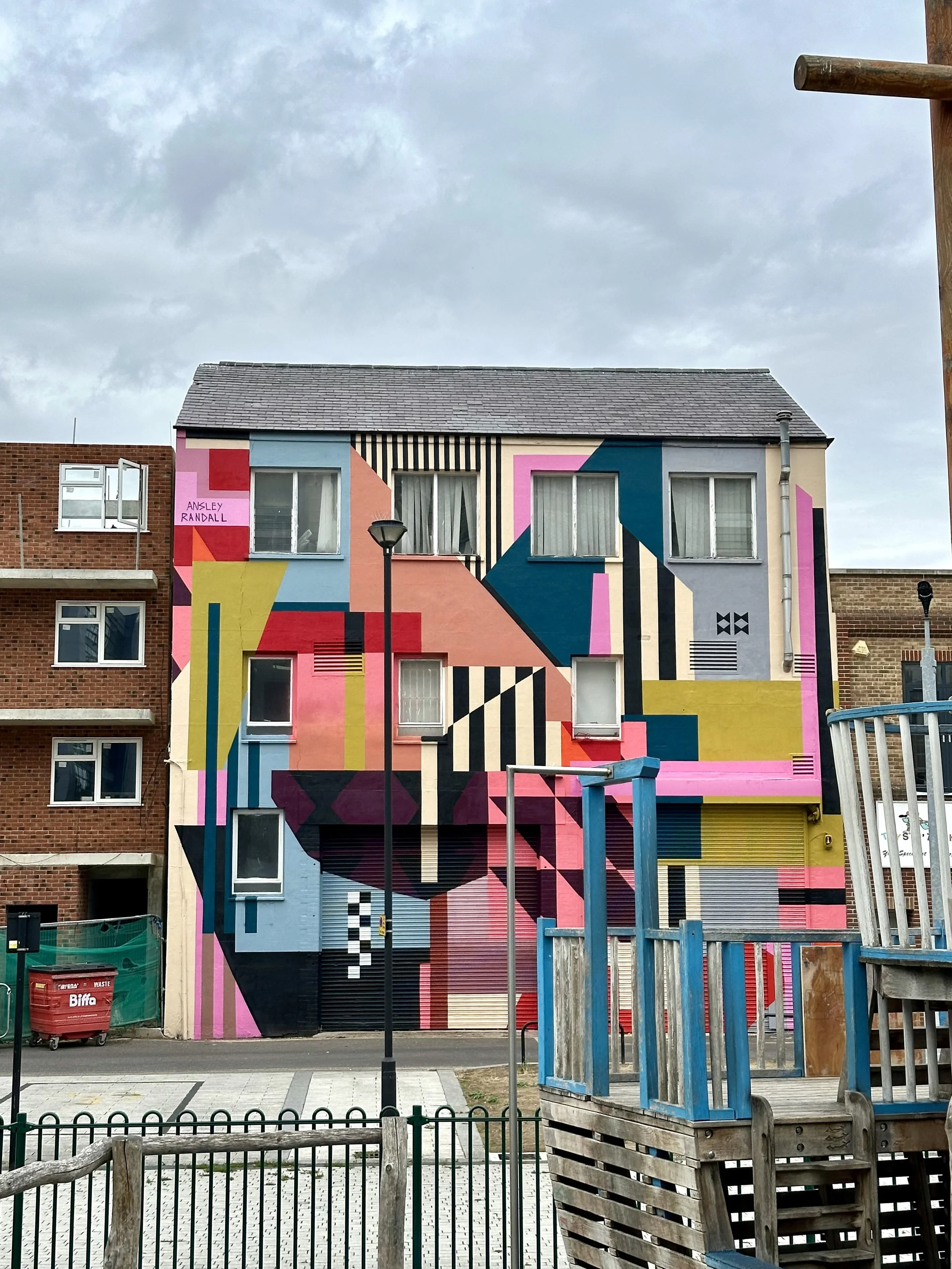 Abstract geometric street art by Ansley Randall incorporating the depth, corners, and recessed walls of a building.