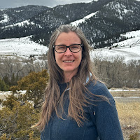 Rochelle Hesford smiling outdoors with snow-covered mountains and trees in the background.