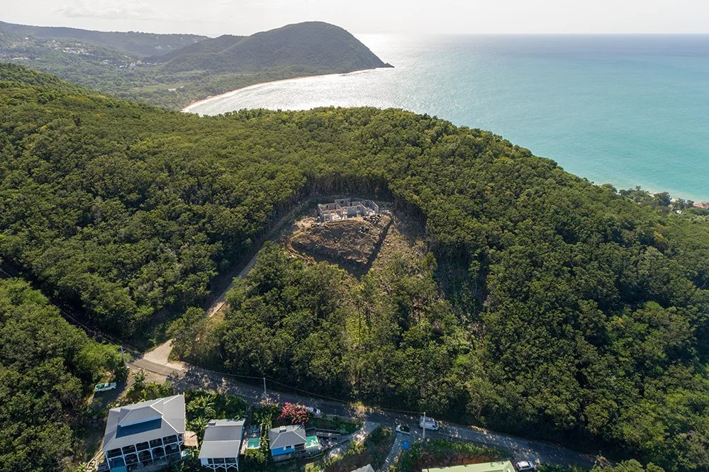 Situé dans la commune de Deshaies, une des plus touristiques de Guadeloupe, le projet de Pearl Houses se déploie sur un morne vert avec une vue directe sur la plage de la Perle.