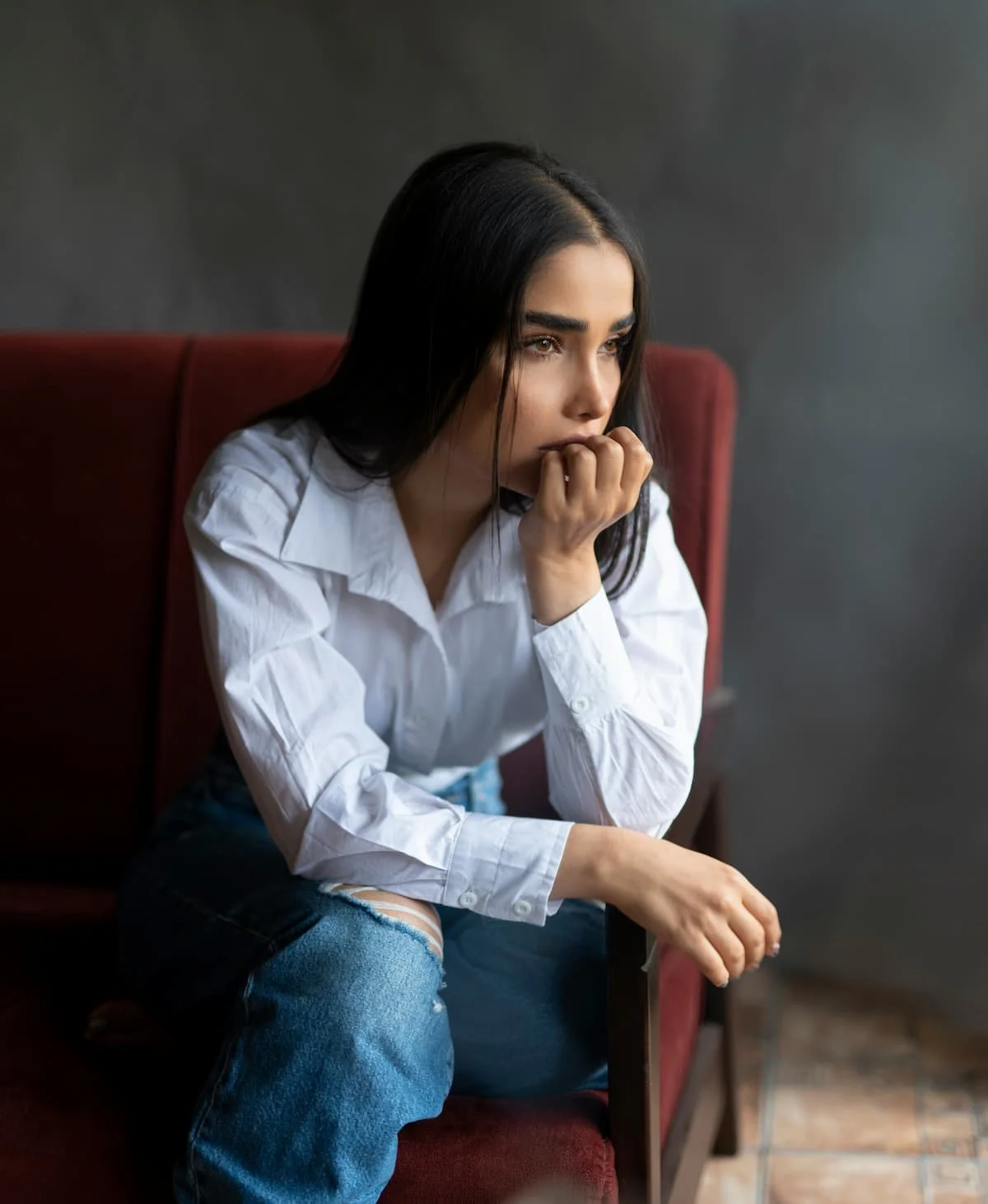 Woman sitting alone with anxious expression during birth trauma and postpartum depression therapy in Miami FL