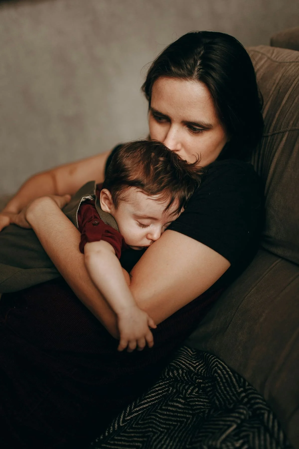 Mother holding baby on couch during postpartum OCD and intrusive thoughts therapy in Miami FL