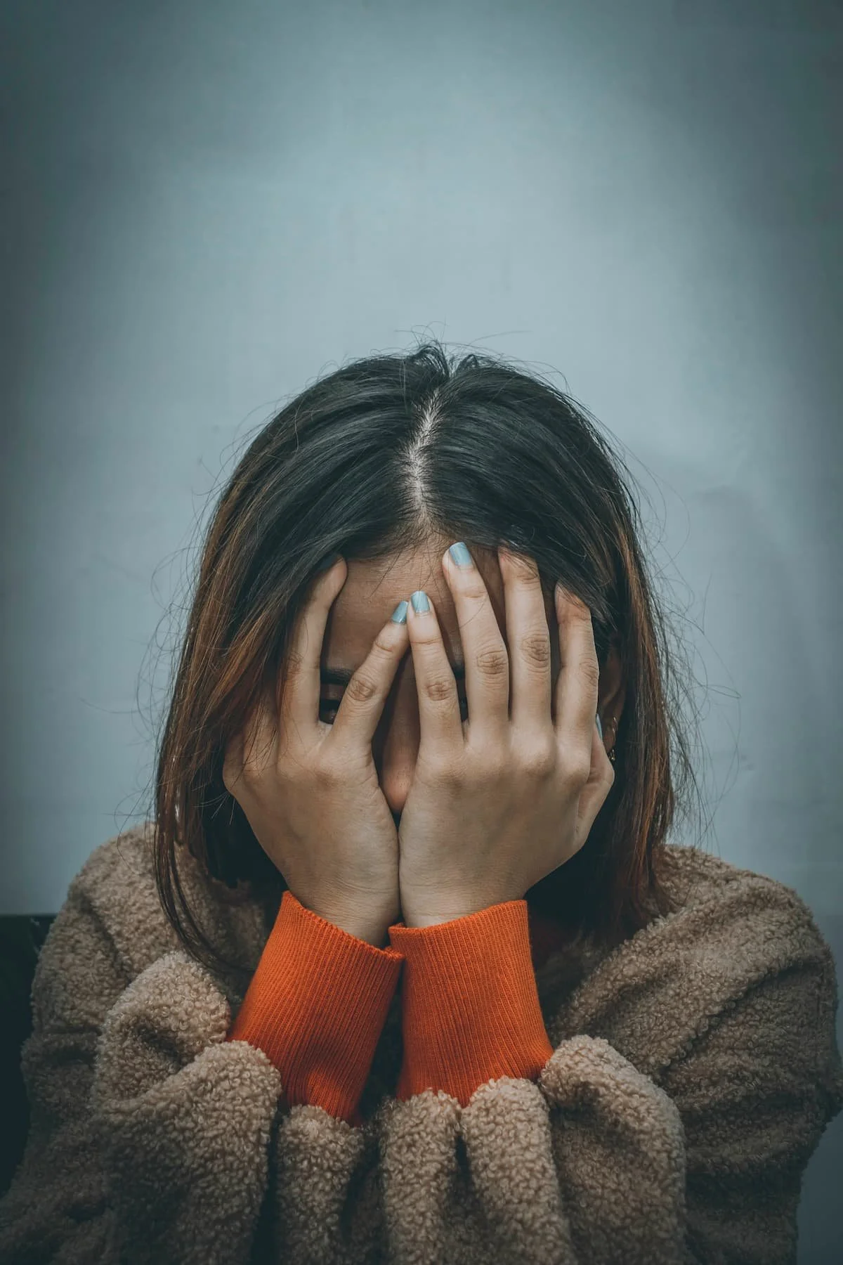 Woman covering face with hands during postpartum intrusive thoughts therapy in Miami FL