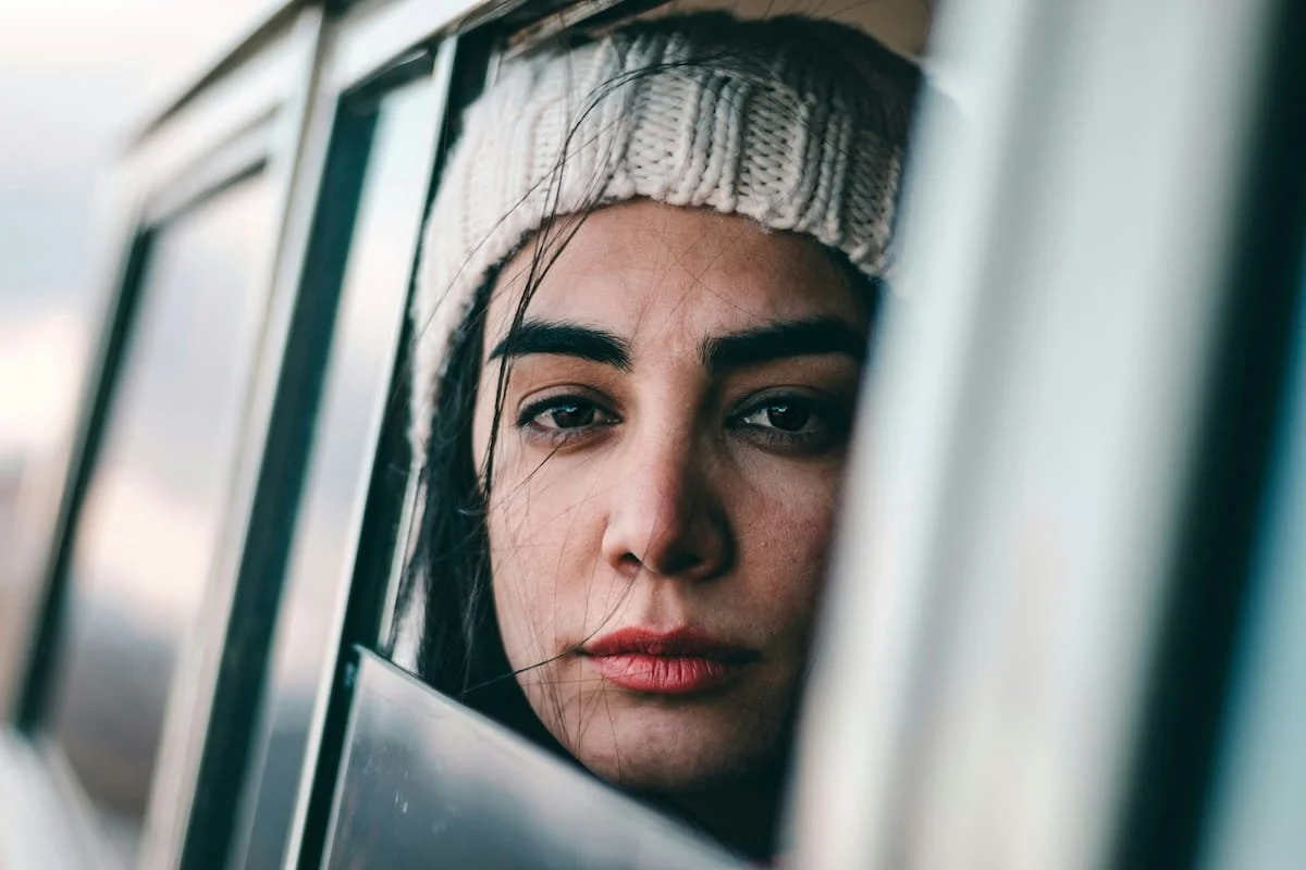 Woman looking out car window experiencing anxiety after infertility and pregnancy loss therapy in Miami FL