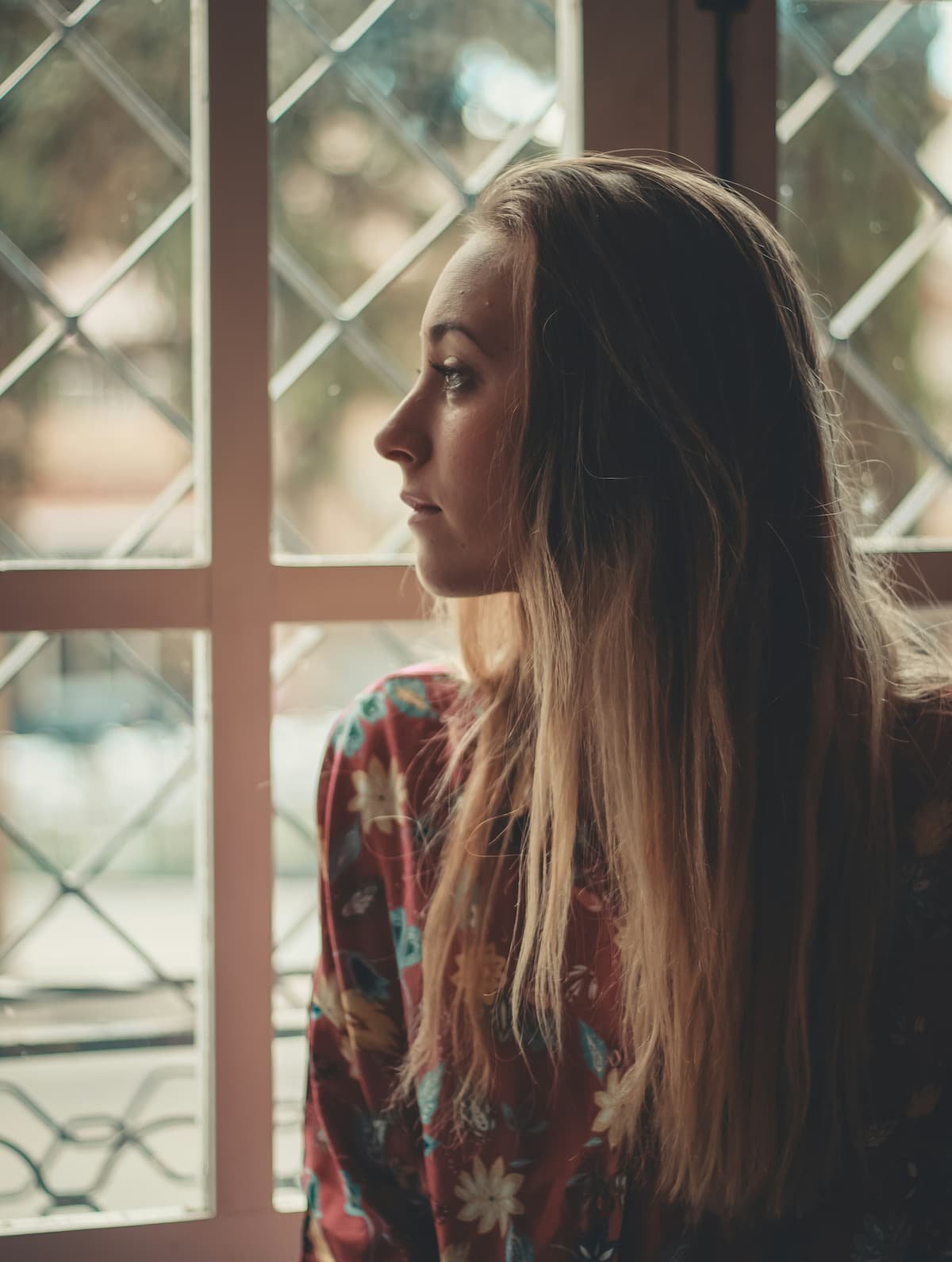 Woman looking out window during postpartum depression therapy after infertility and pregnancy loss in Miami FL
