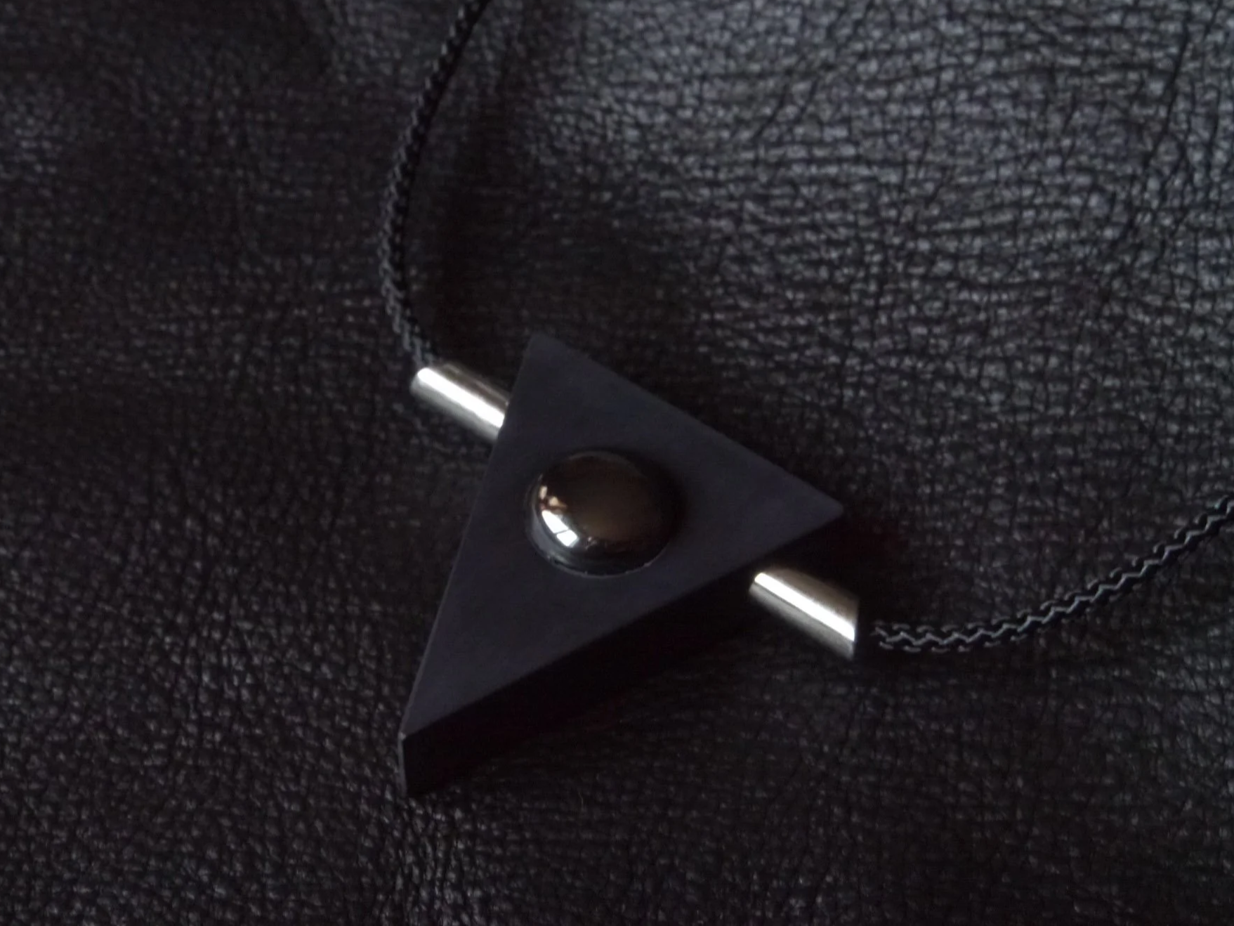 OPPOSITES necklace by ISAROS, black corian triangular pendant with hematite cabochon and steel rods, material tension form