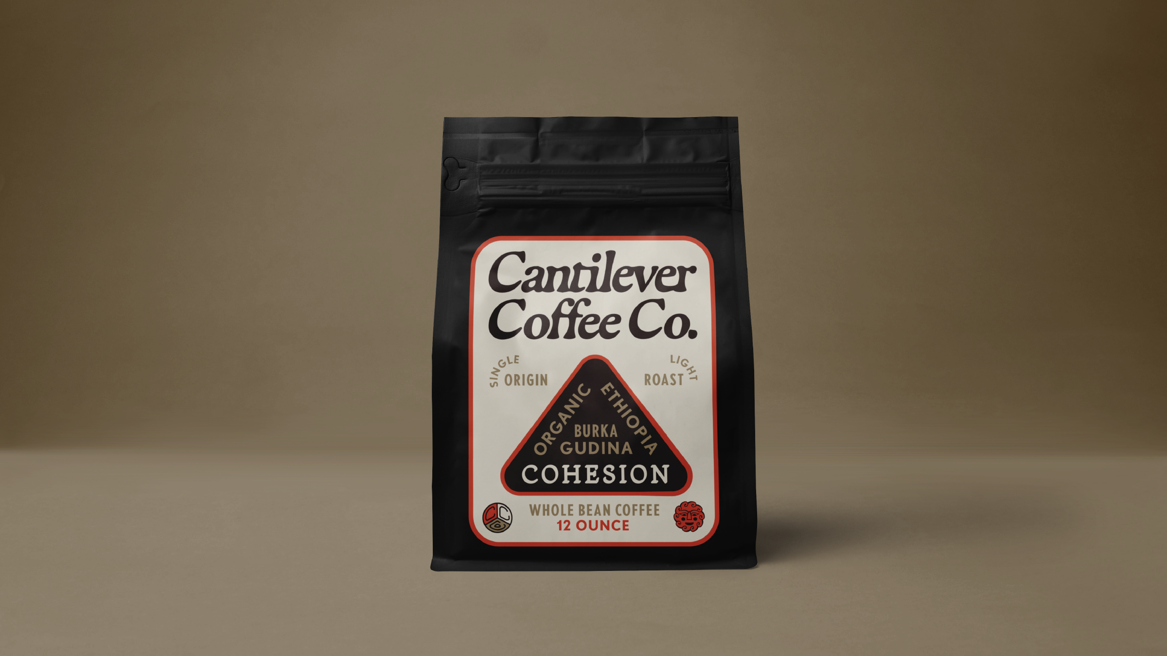 A black bag of Canilever Coffee Co. whole bean coffee labeled 'Cohesion' from Ethiopia, Burundi, and Gudina, 12 ounces, with a beige background.