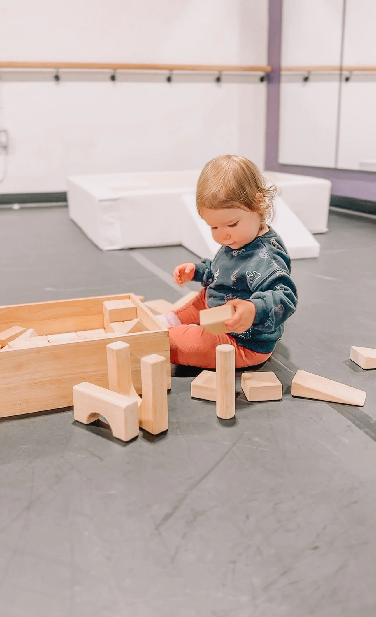 Young child playing with wooden blocks in a playroom.