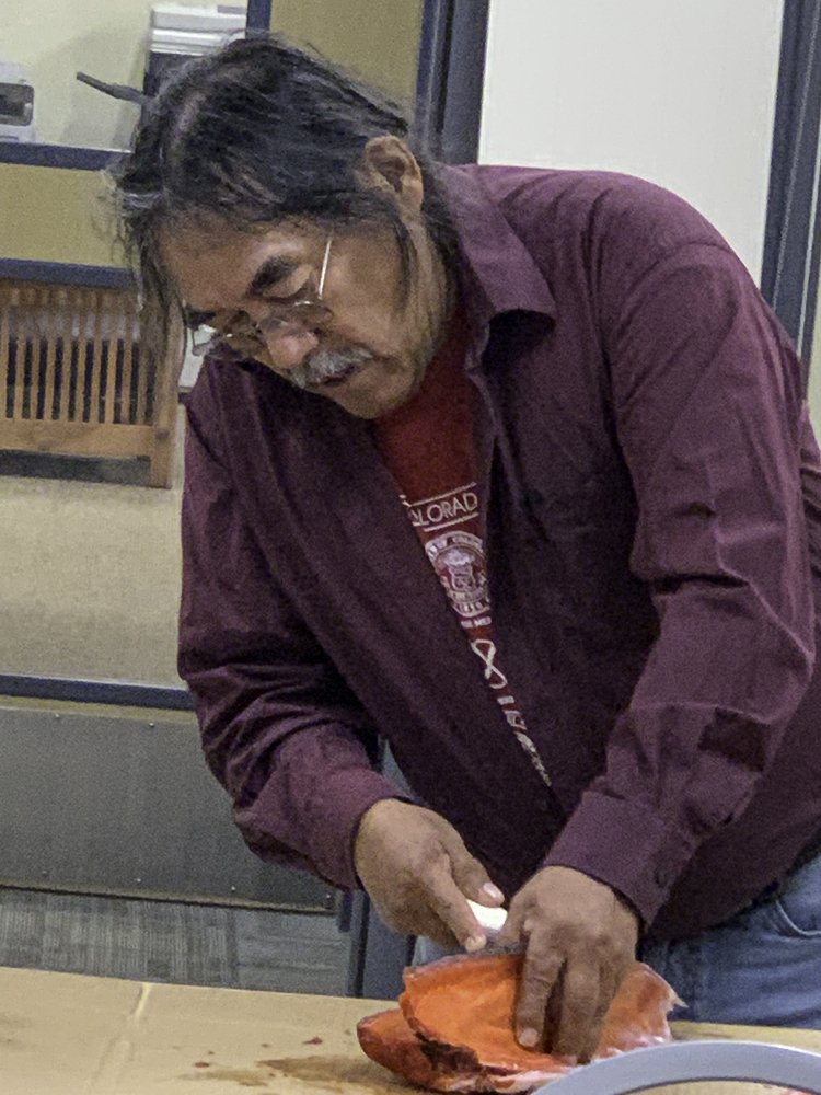 Male Elder fileting salmon inside on a table