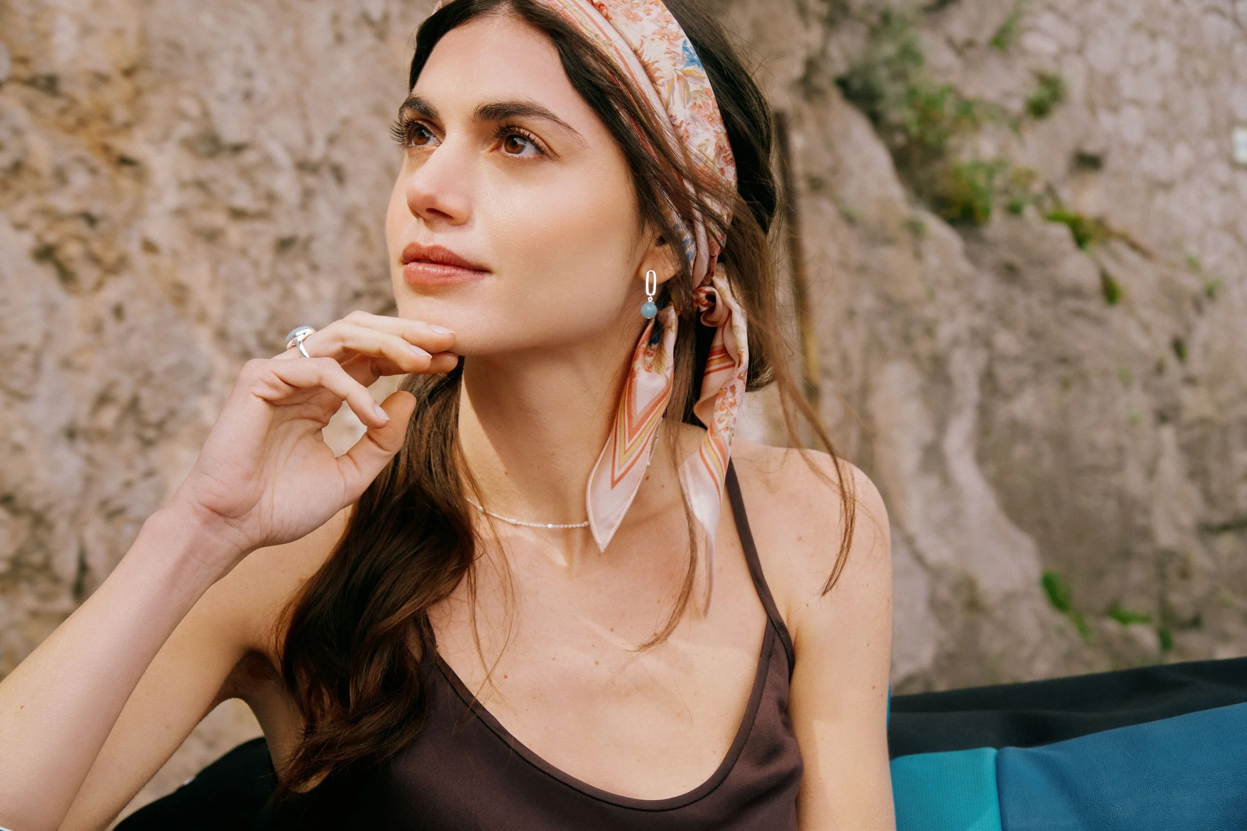 Model with headscarf and rocks behind her.