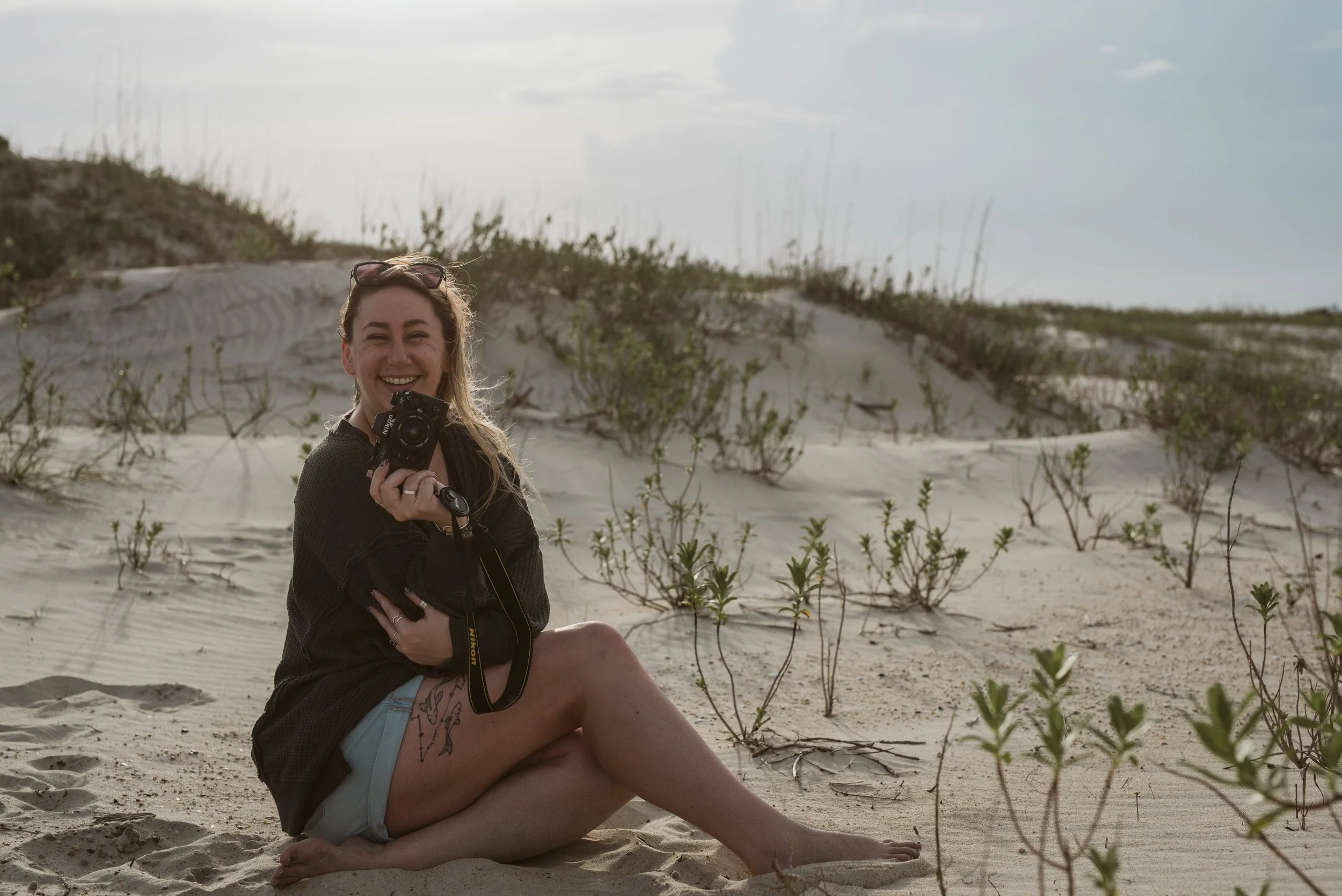 girl sitting on the beach holding a film camera