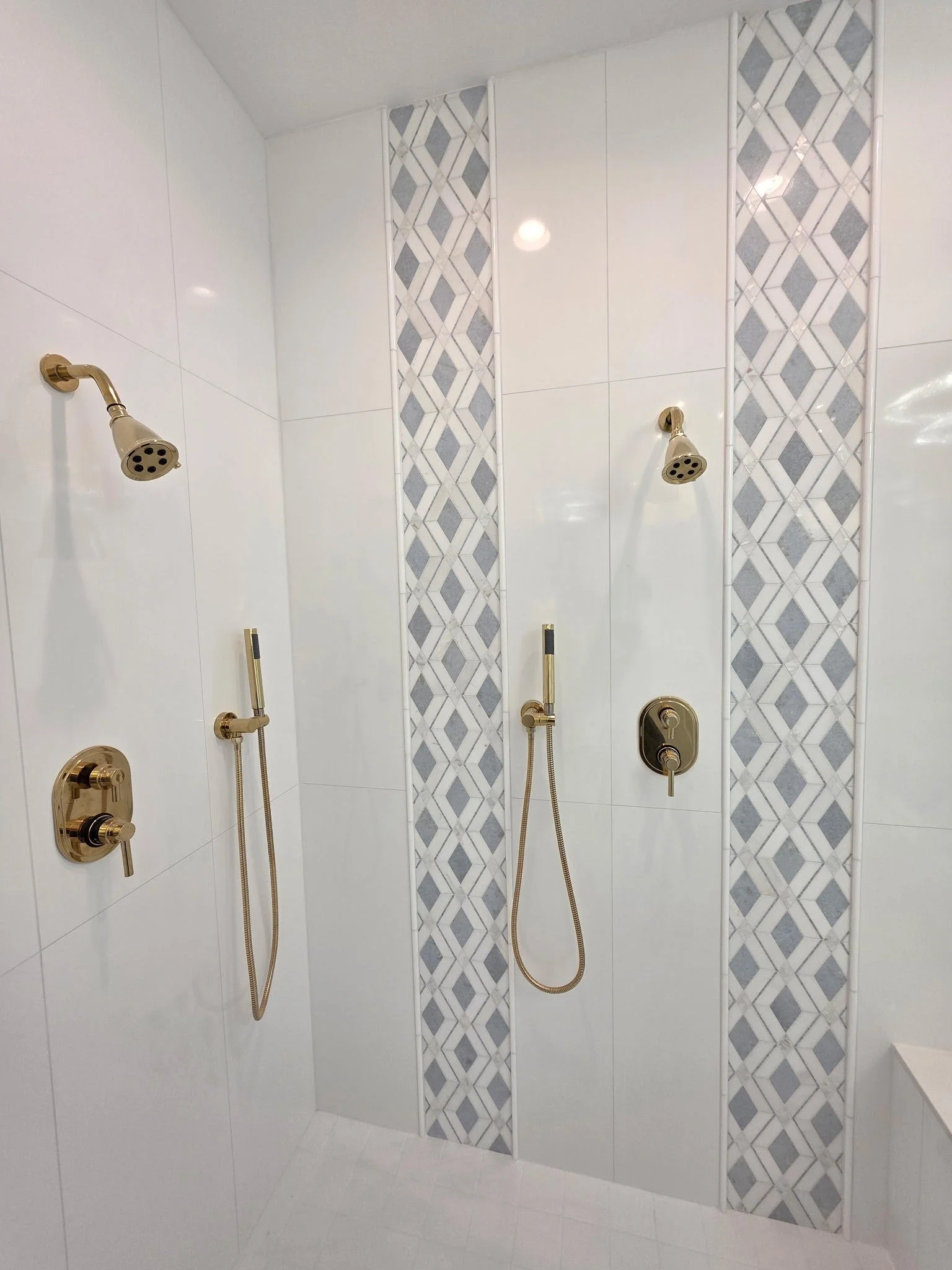 Crisp white tile, patterned accents and complimentary fixtures come together for a timeless finish.