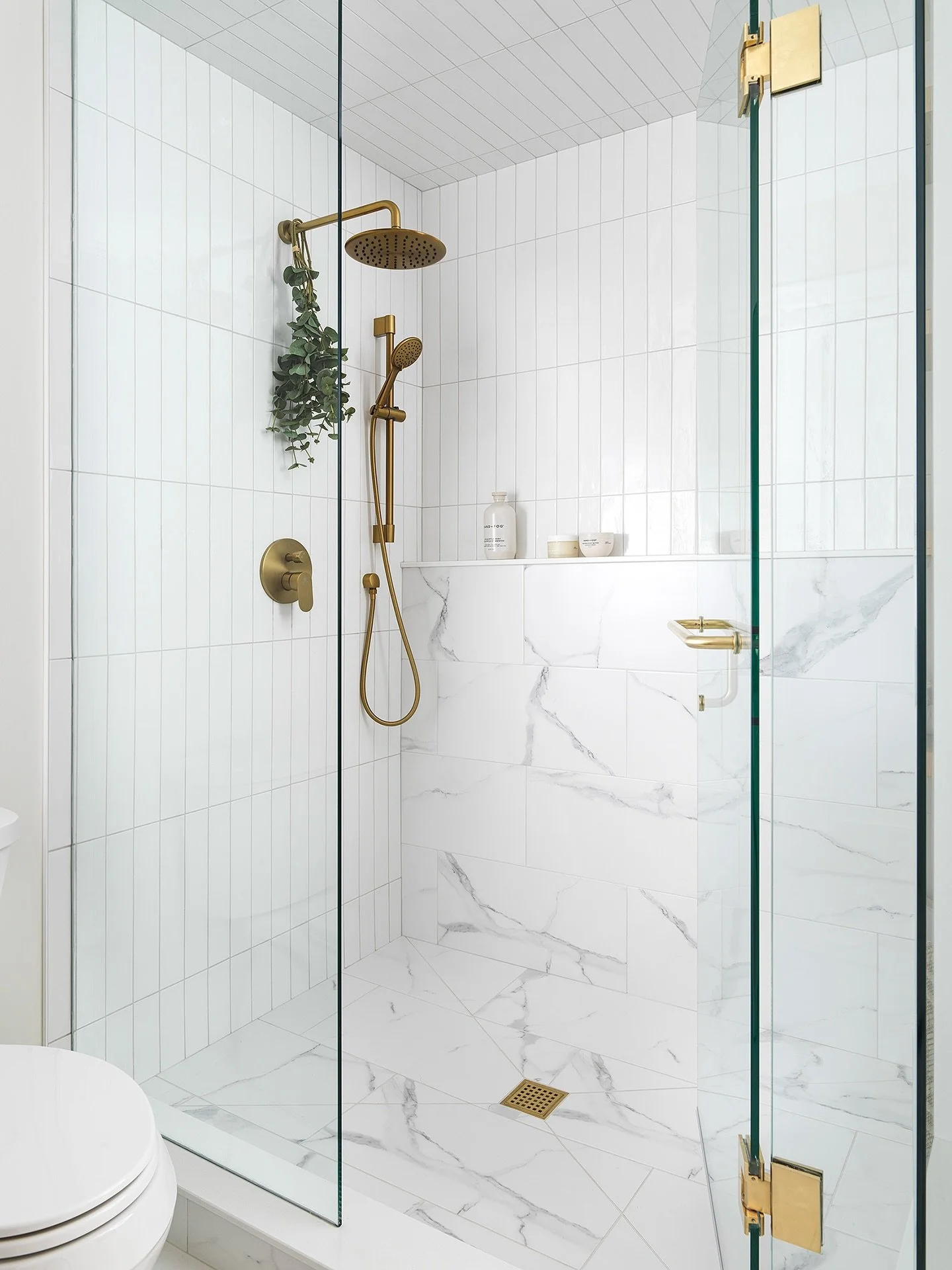 🚿✨ Proof that function and beauty can totally be best friends. From the warm gold fixtures to the crisp marble and vertical tile, every detail here is designed to make your morning routine feel like a spa day. Now if only the coffee could appear in 