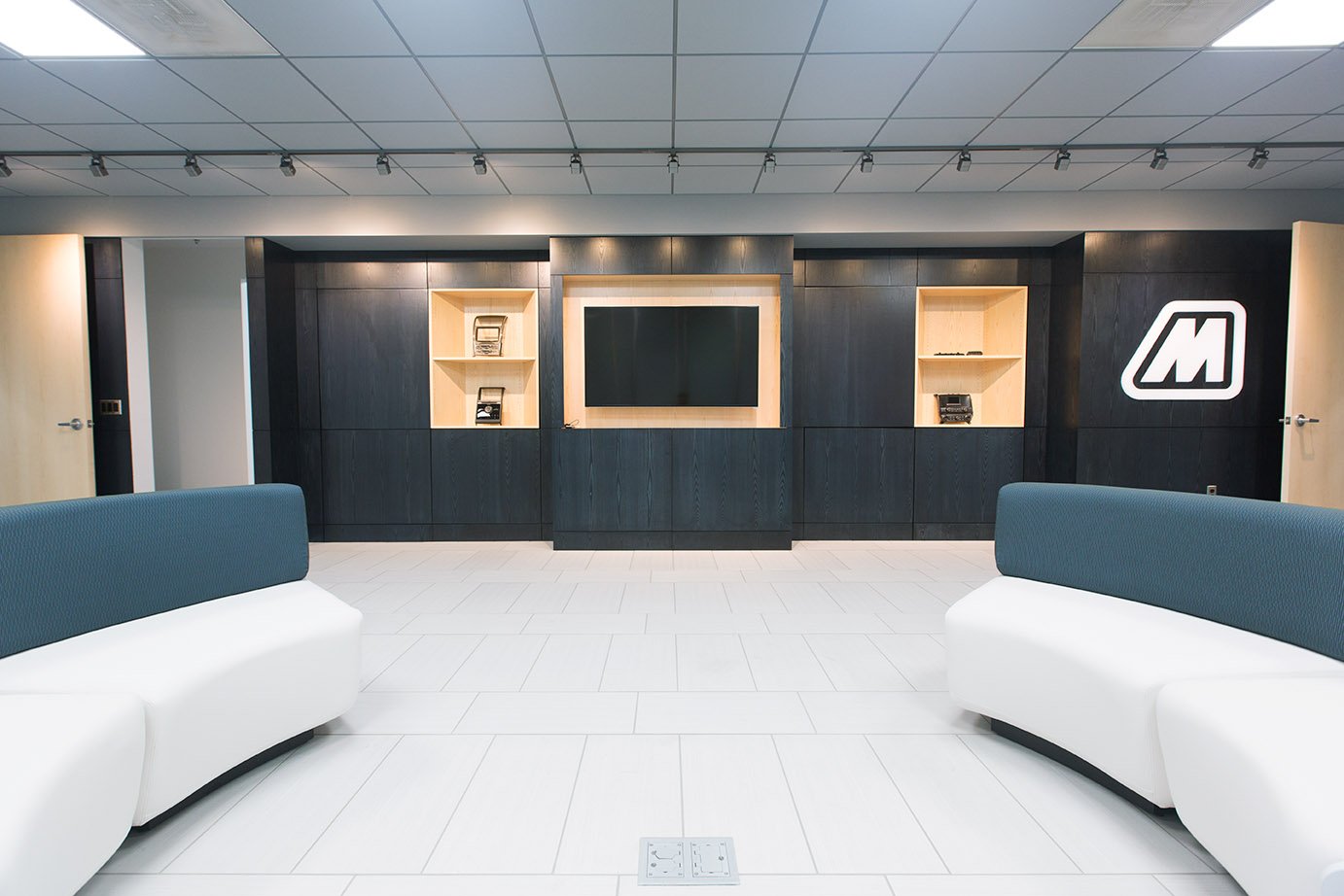 A lounge area with a tv and two rounded couches.