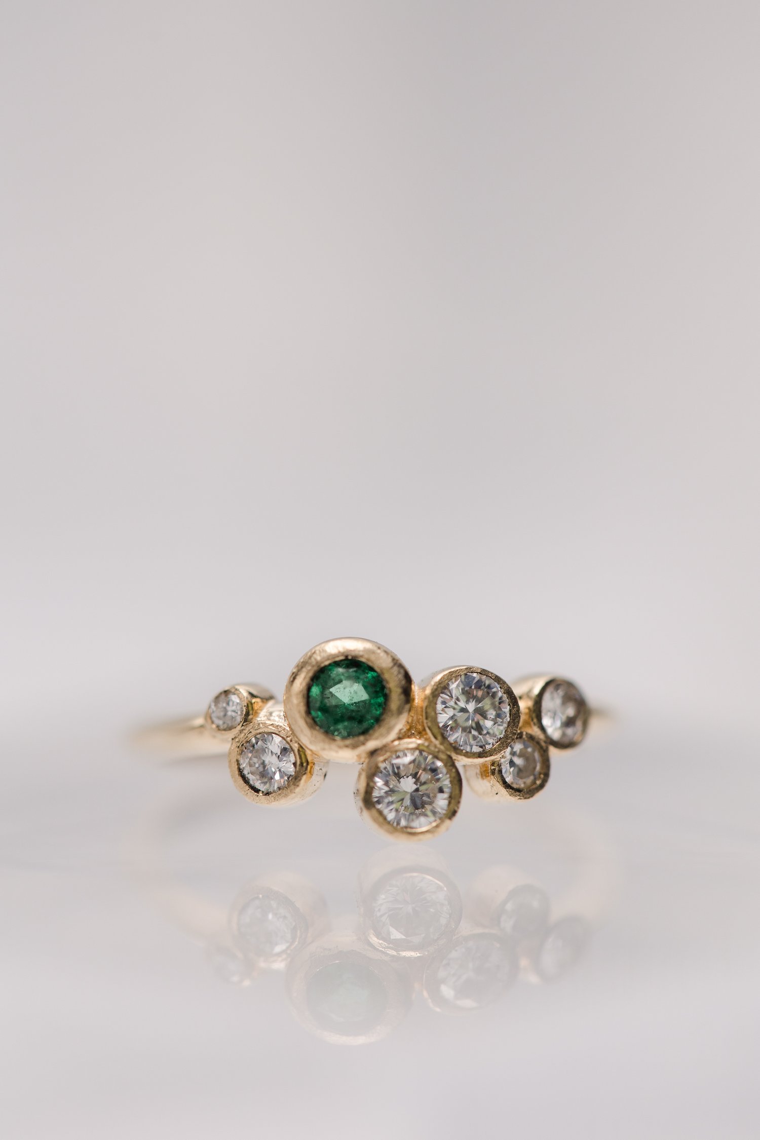 custom made bezel set yellow gold cluster style ring with diamonds and emeralds designed by Alexandria &amp; Company fine jewelers