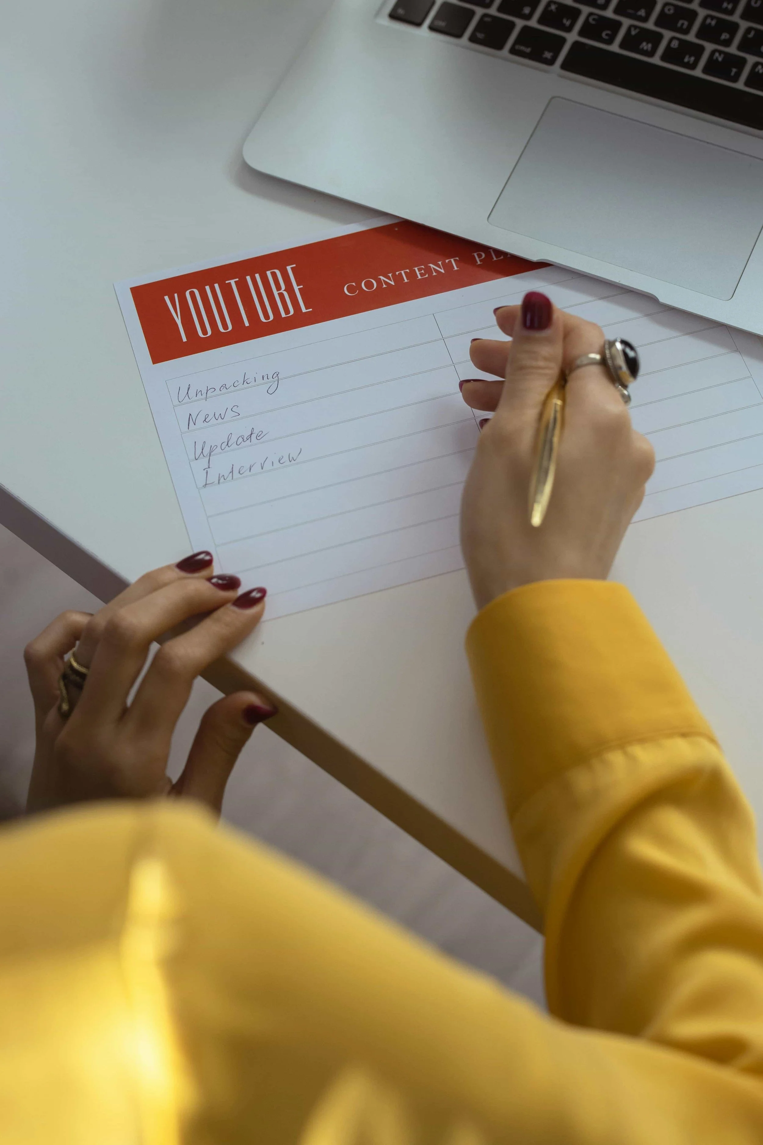 A person writing content ideas on a YouTube content planner, representing the content-first strategy approach of a fractional marketing agency.