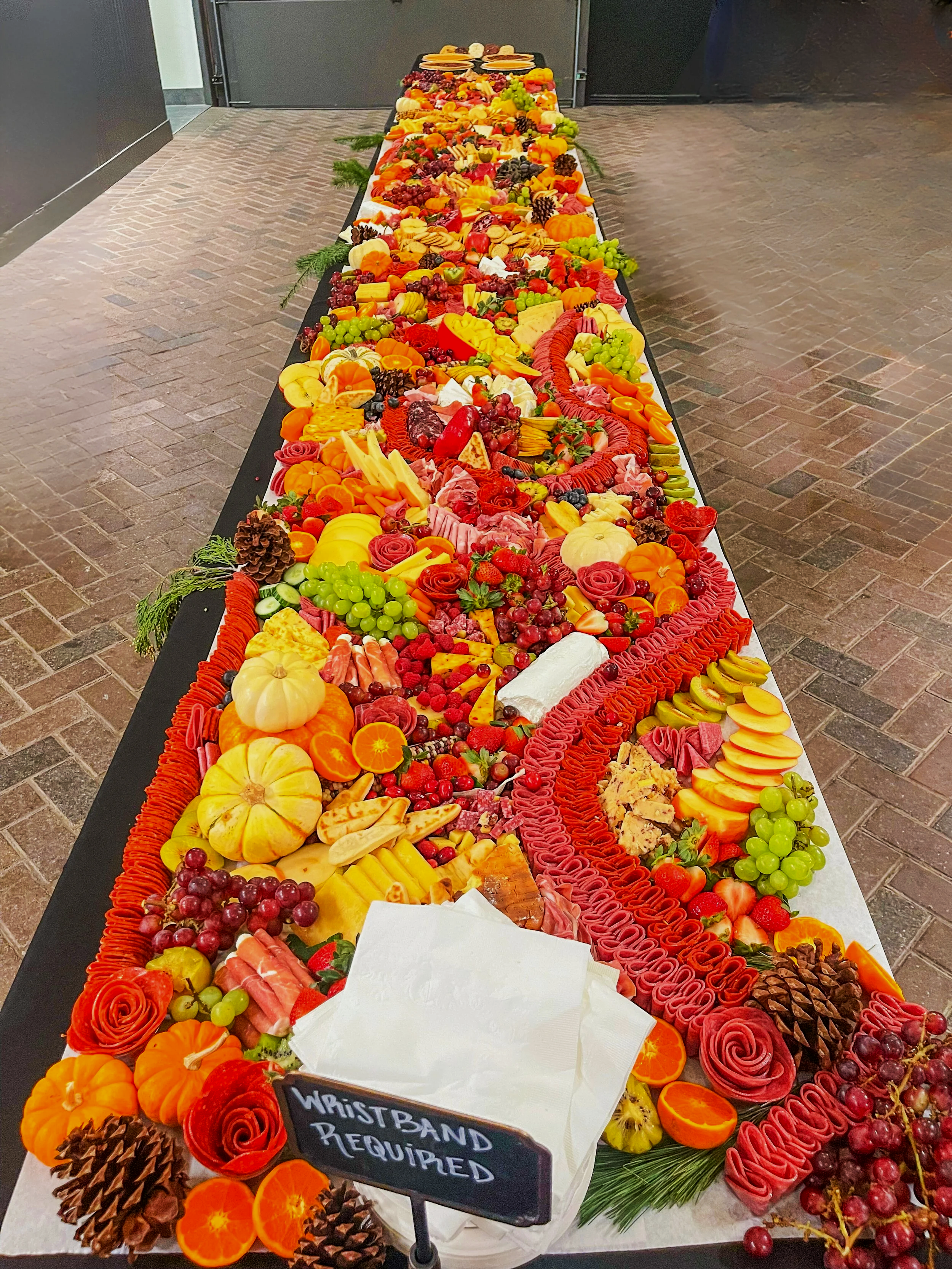 A long table decorated with various fruits, cheeses, and meats arranged in a colorful display for a celebration or event.