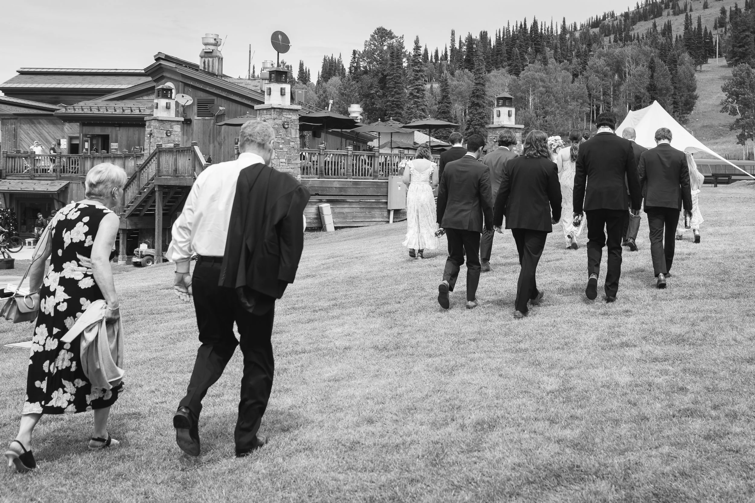Documentary style wedding photography, Grand Targhee Resort; wedding party walks across lawn of resort