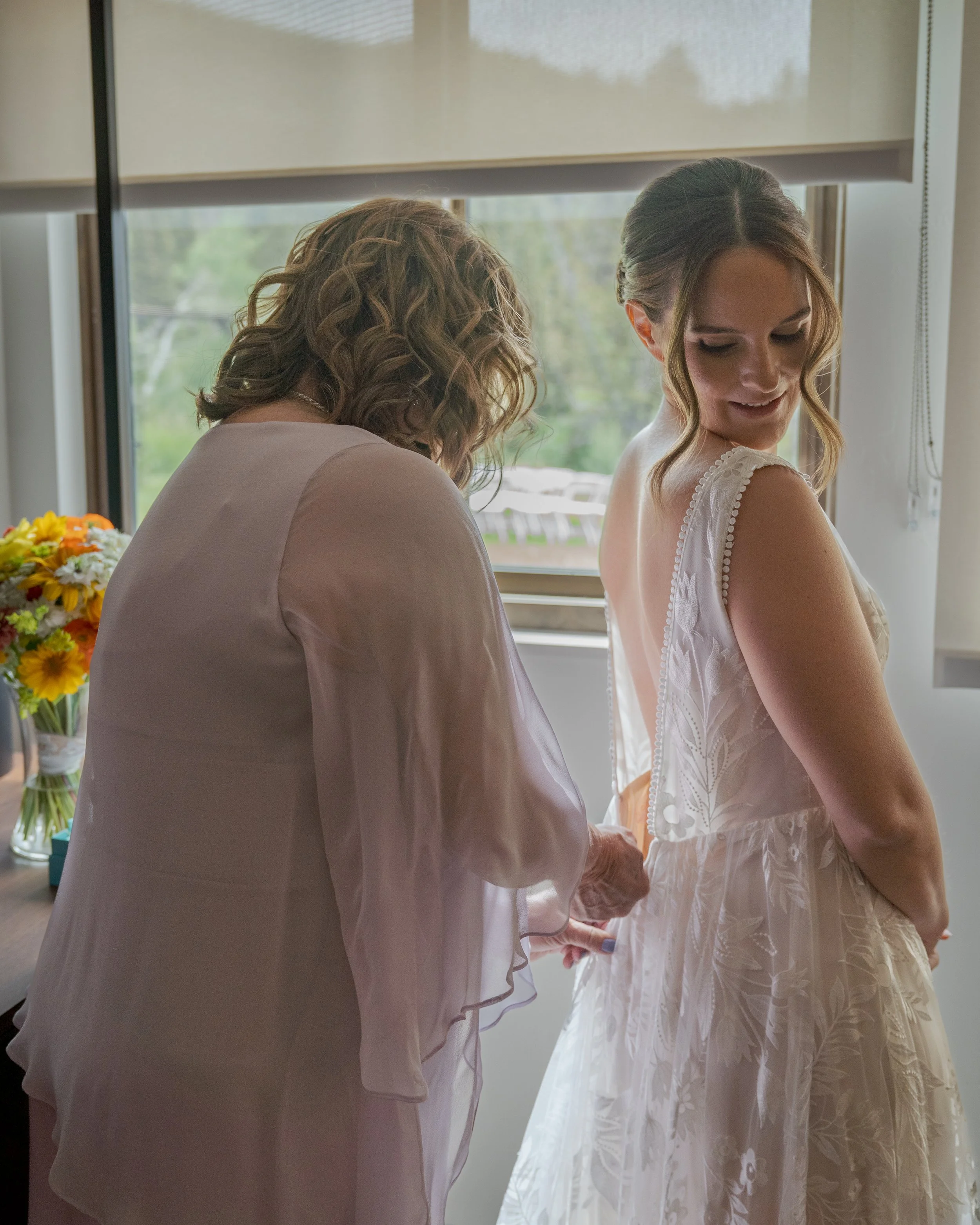 Mother helping bride zip up wedding dress at Grand Targhee Resort, documentary wedding photography style