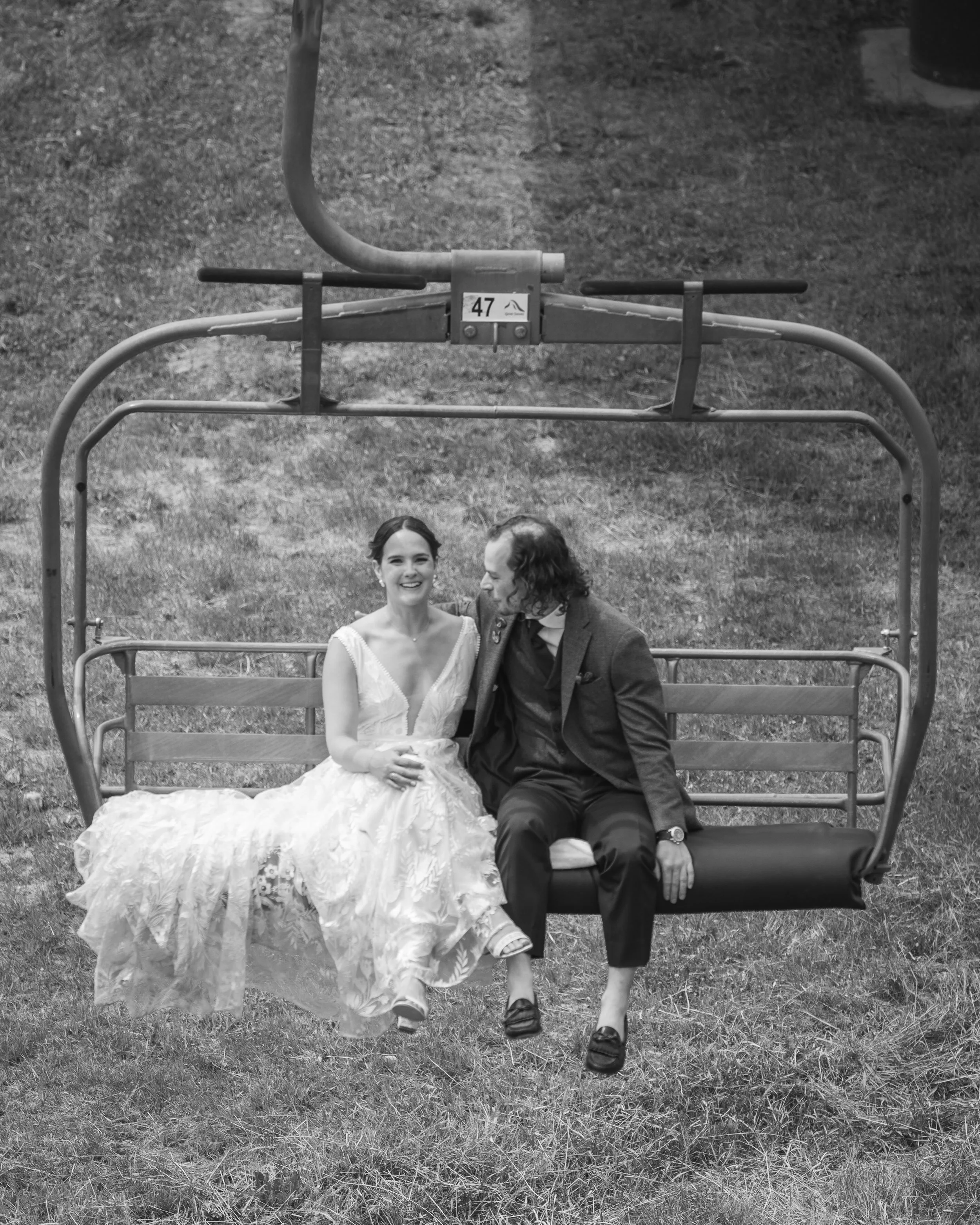 Grand Targhee Resort, documentary Wedding photography; bride and groom sit on ski lift, bride looking at camera with big smile, groom looking at her with arm around her